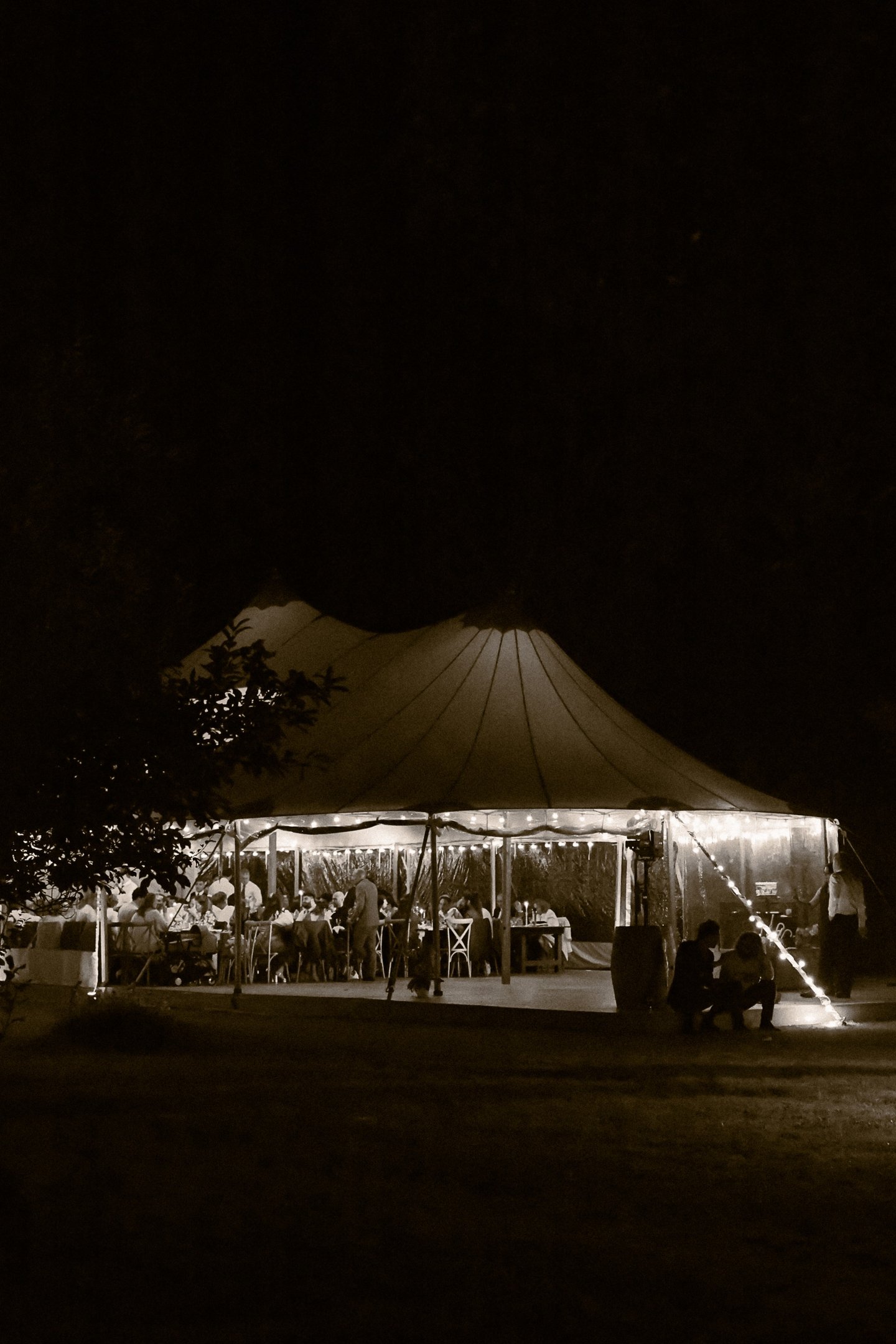 Dîner de mariage, tente de réception éclairée, guirlandes lumineuses. Astuce mariage hors-saison.