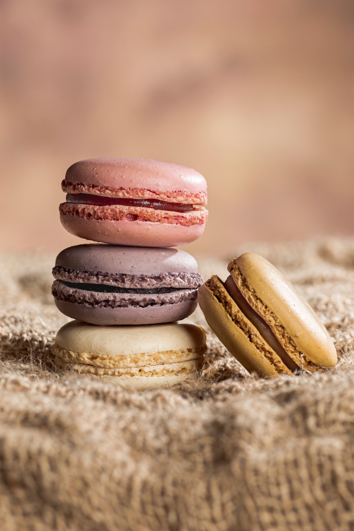 4 macarons dont trois empilés sur toile de jute et fond marron clair