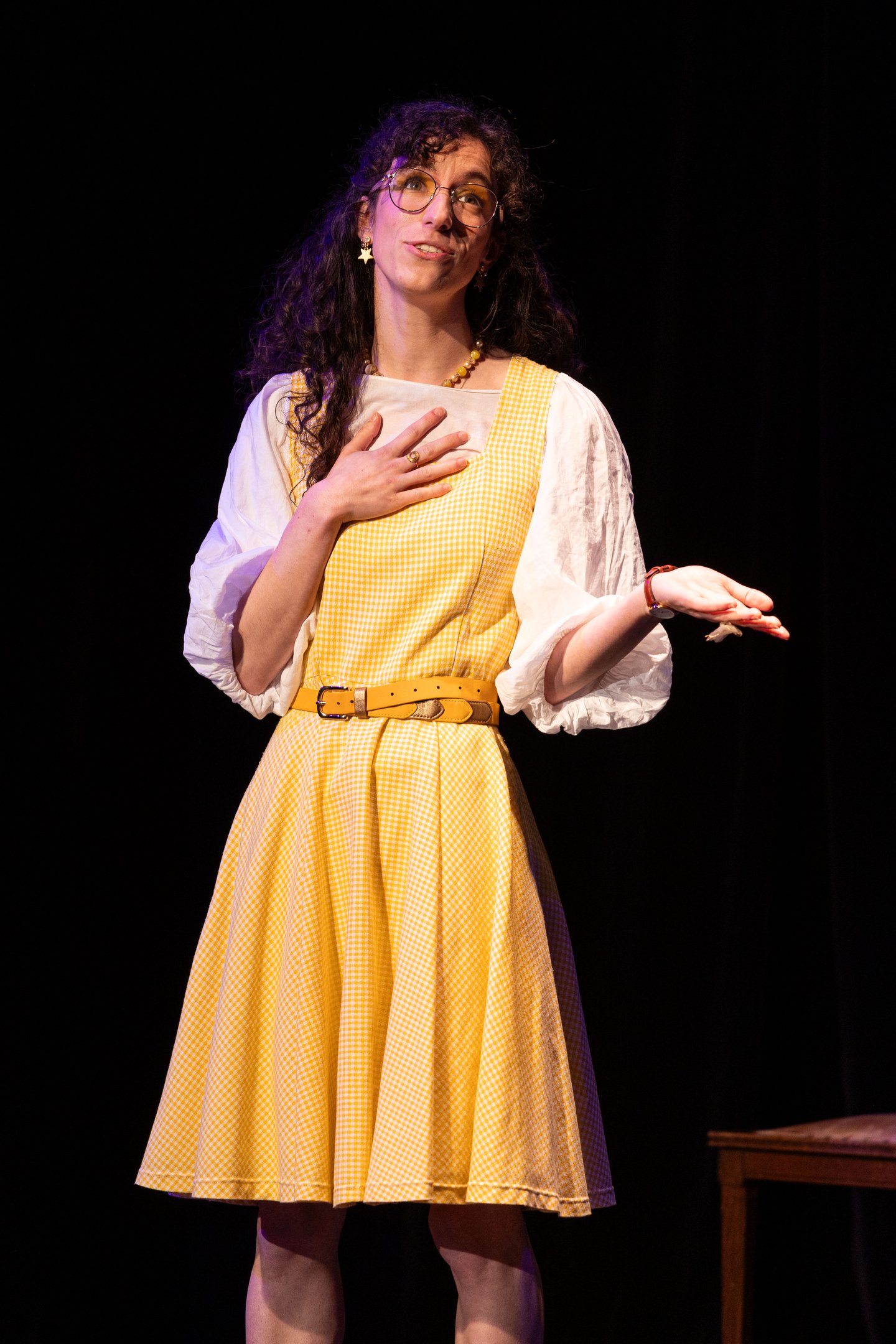Aude Fy dans une pièce de théâtre sur scène en robe jaune