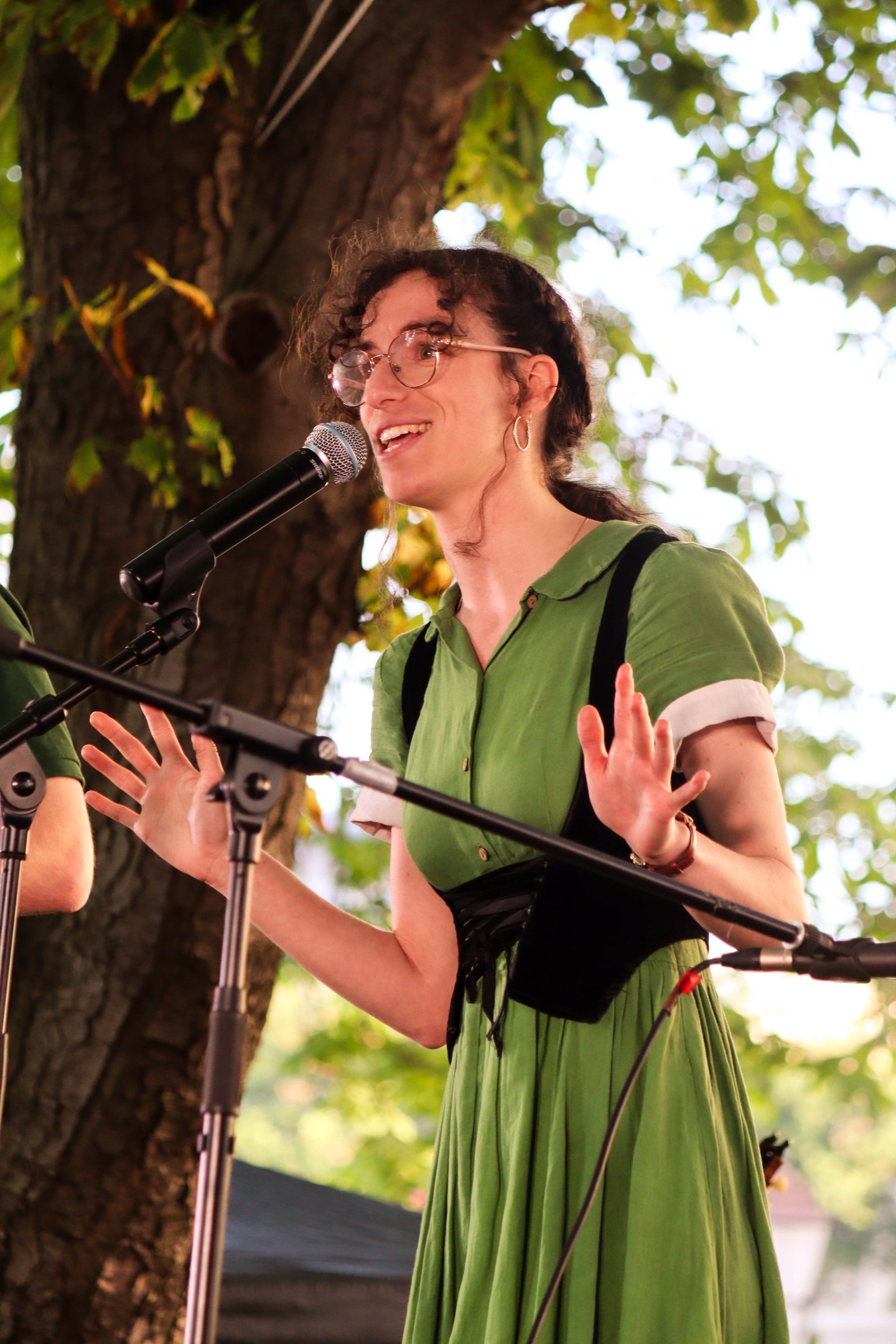 chanteuse interprétant une chanson folk sur scène /singer in a green dress singing into a microphone