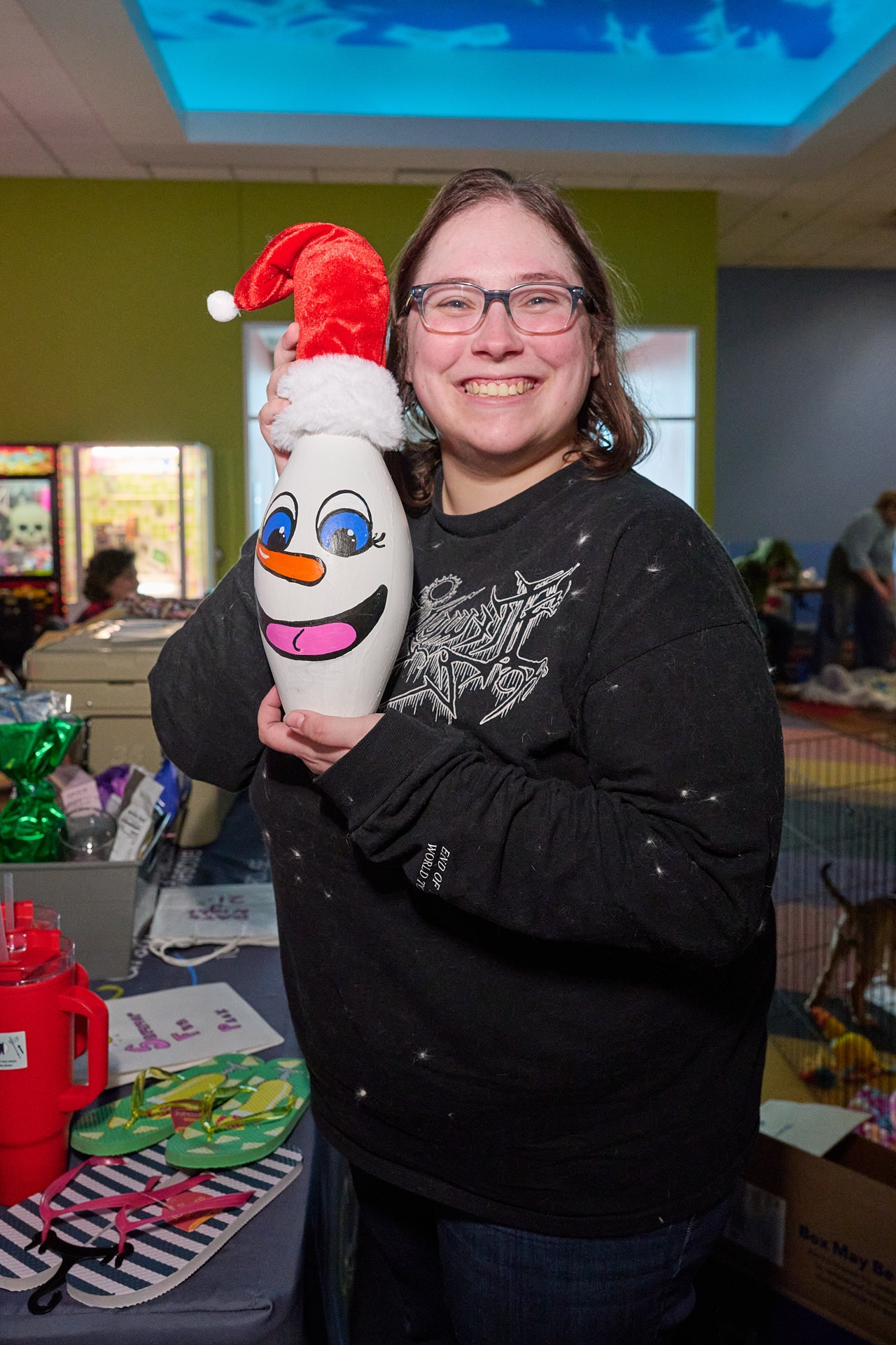 a woman holding a pin with painting and Santa hat