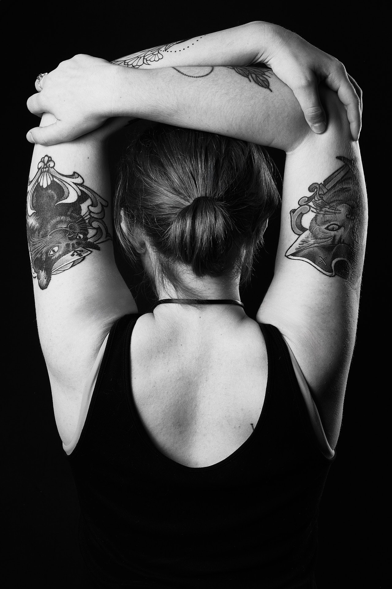 a woman showing her back with cat tattoos on her arms which are stretching around her head
