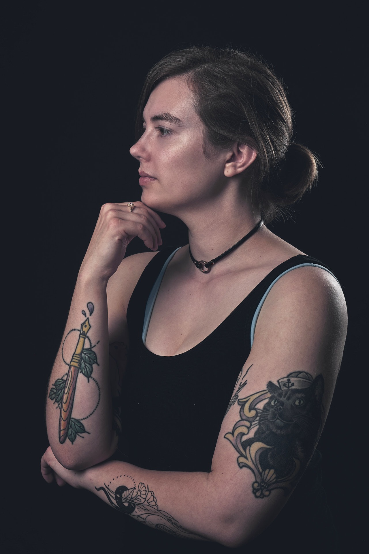 a woman with tattoo of a pen on her right arm and a cat tattoo on her left arm