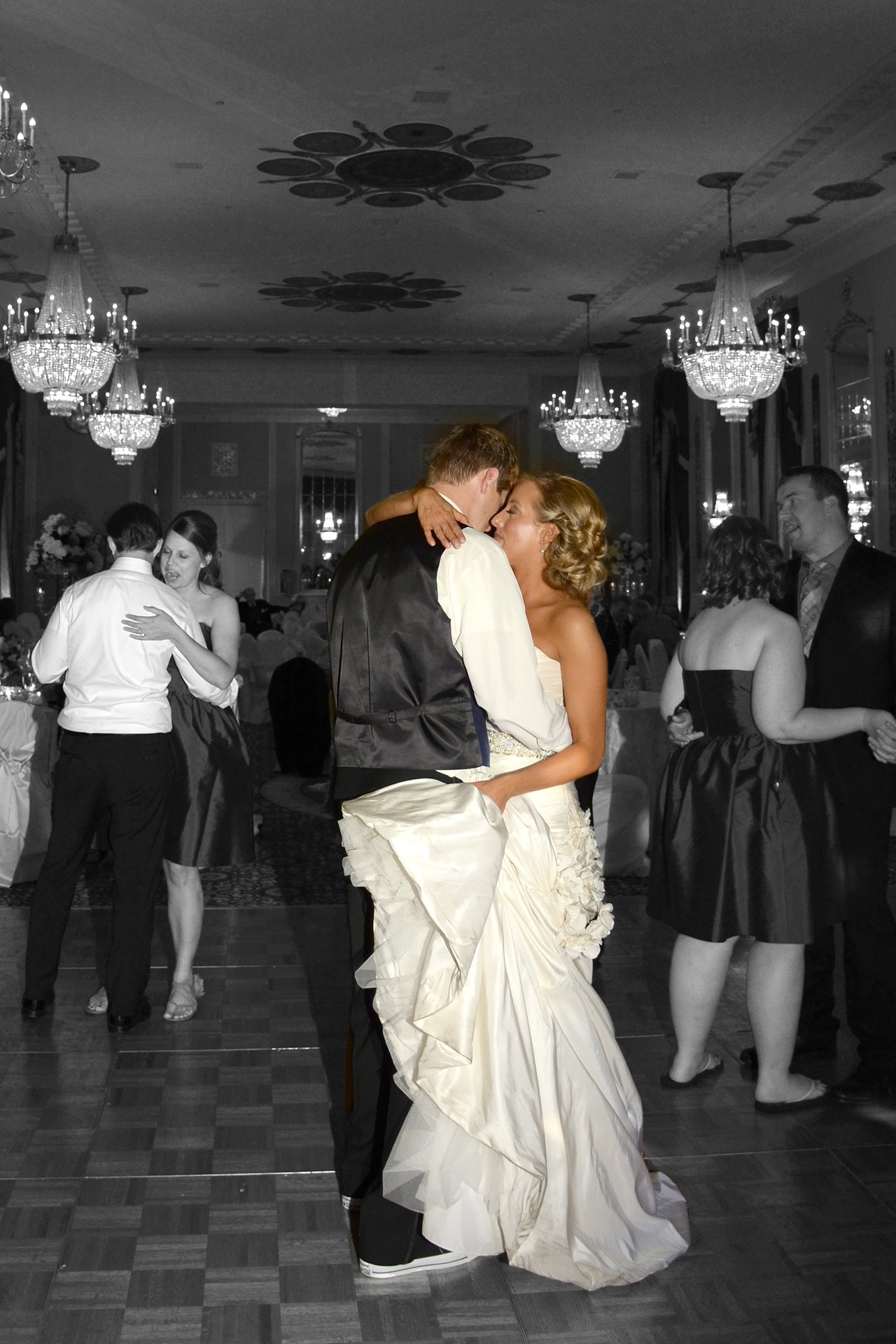 a bride and groom kissing and dancing in a ballroom