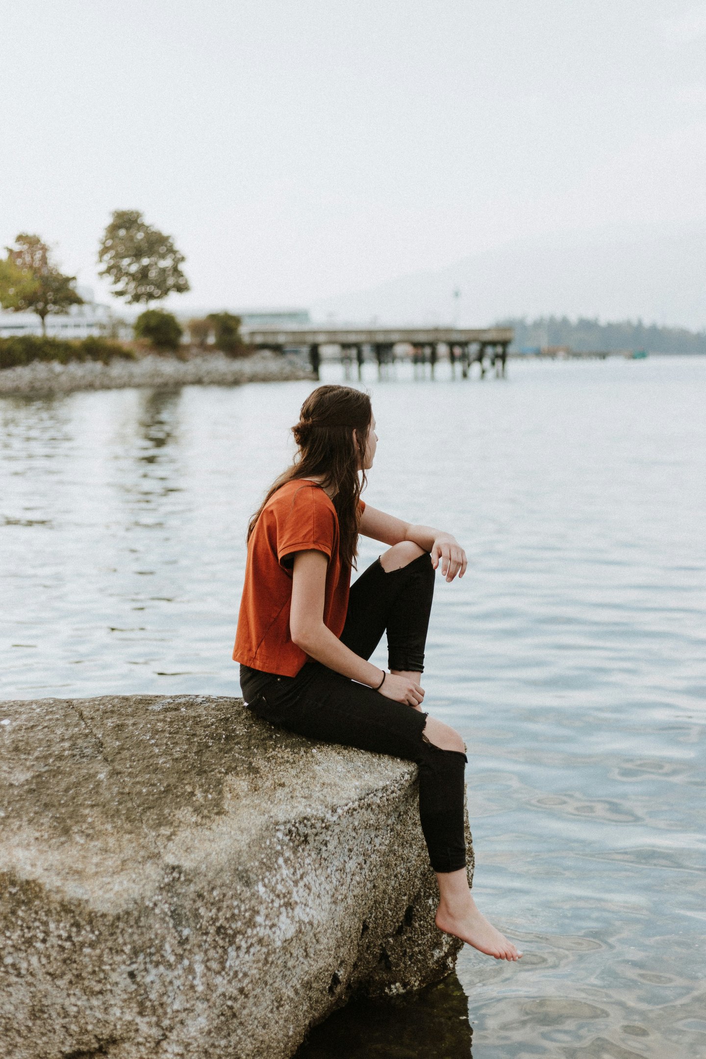 Jeune femme assise sur un rocher au bord d'un lac