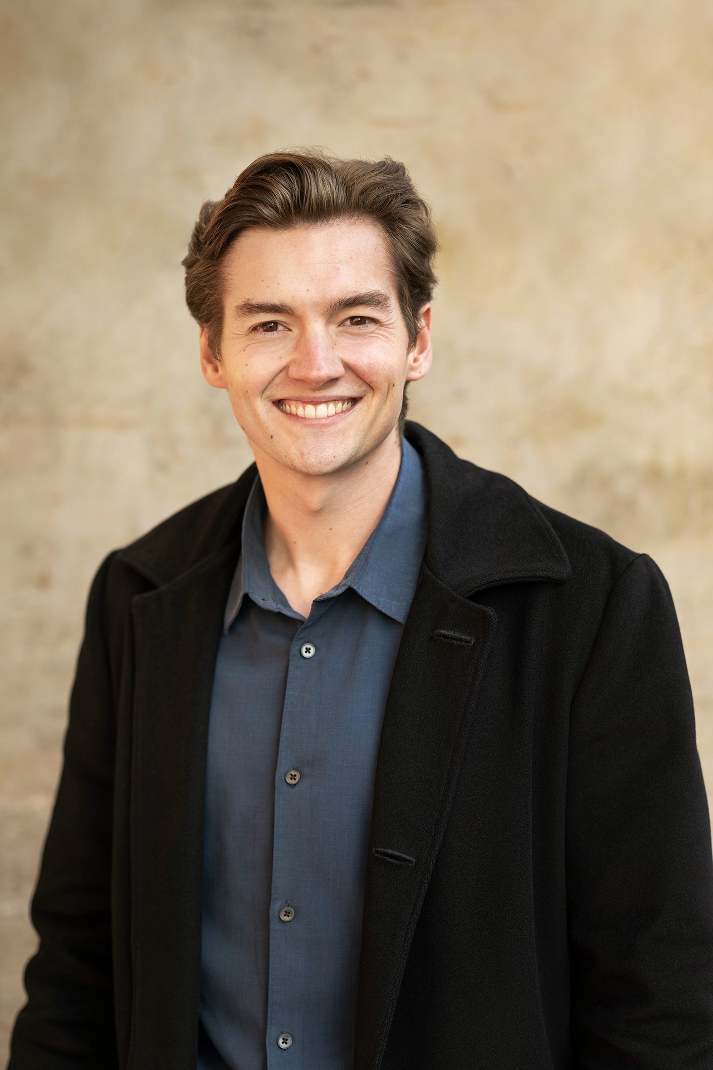 a man in a black jacket and a blue shirt