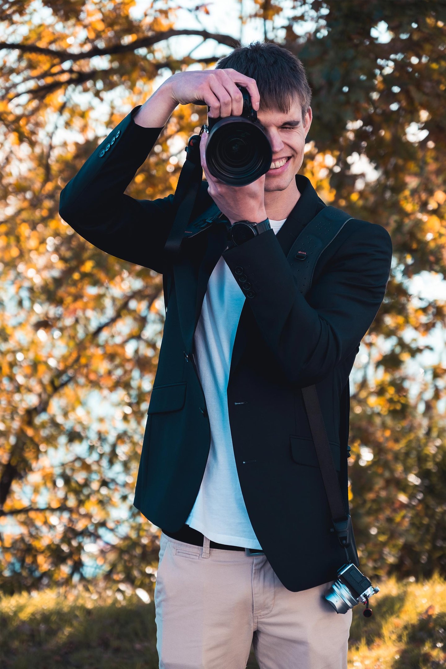 Fotograf Joel Pingel fotografiert lächelnd in herbstlicher Umgebung. Action-Portrait von Just Perspectives.