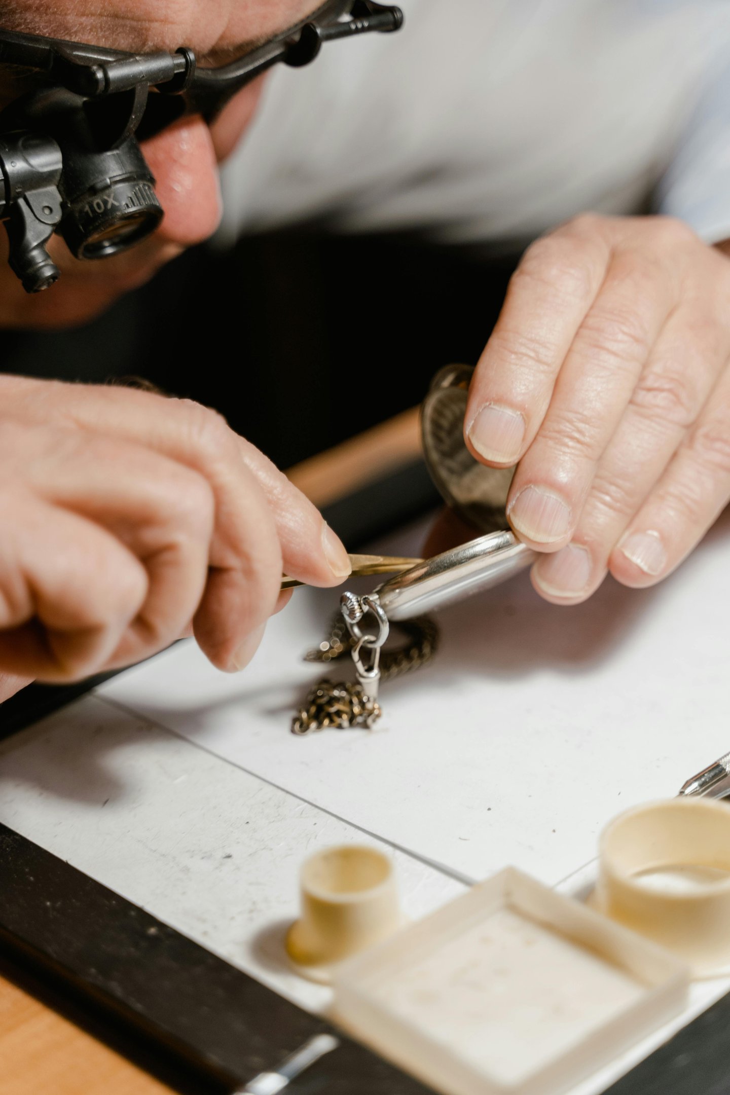 a man wearing magnifying glasses working on repairing a watch