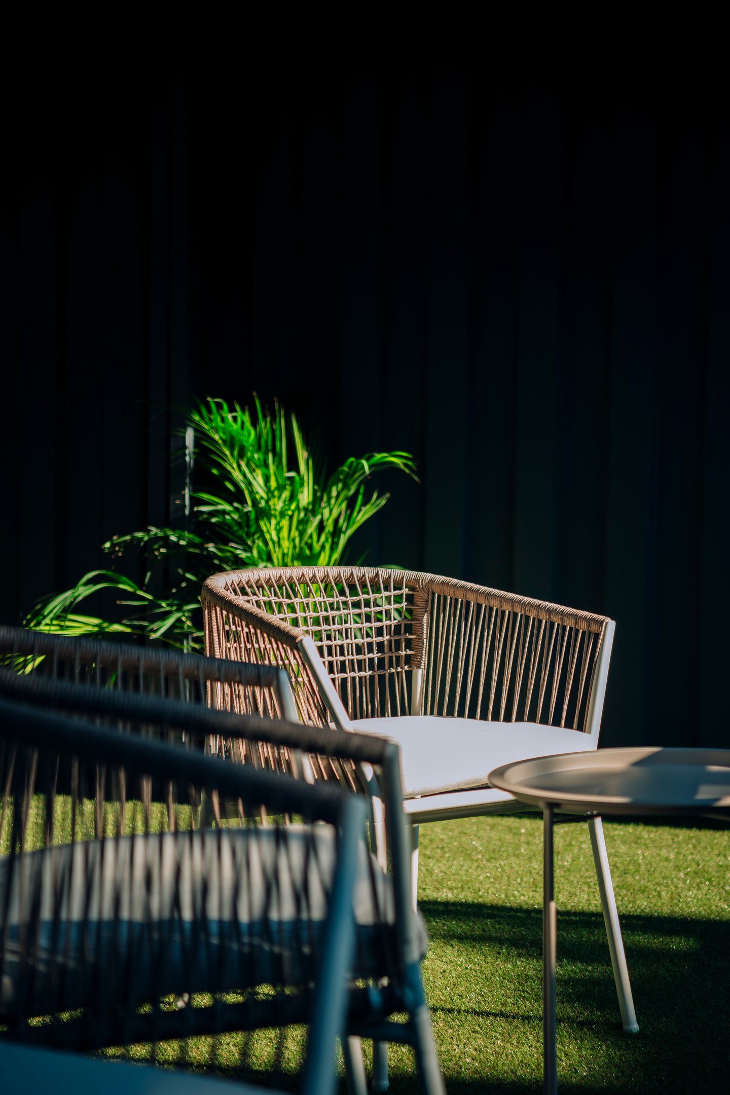 Detalle de mobiliario exterior con silla de fibras naturales y vegetación