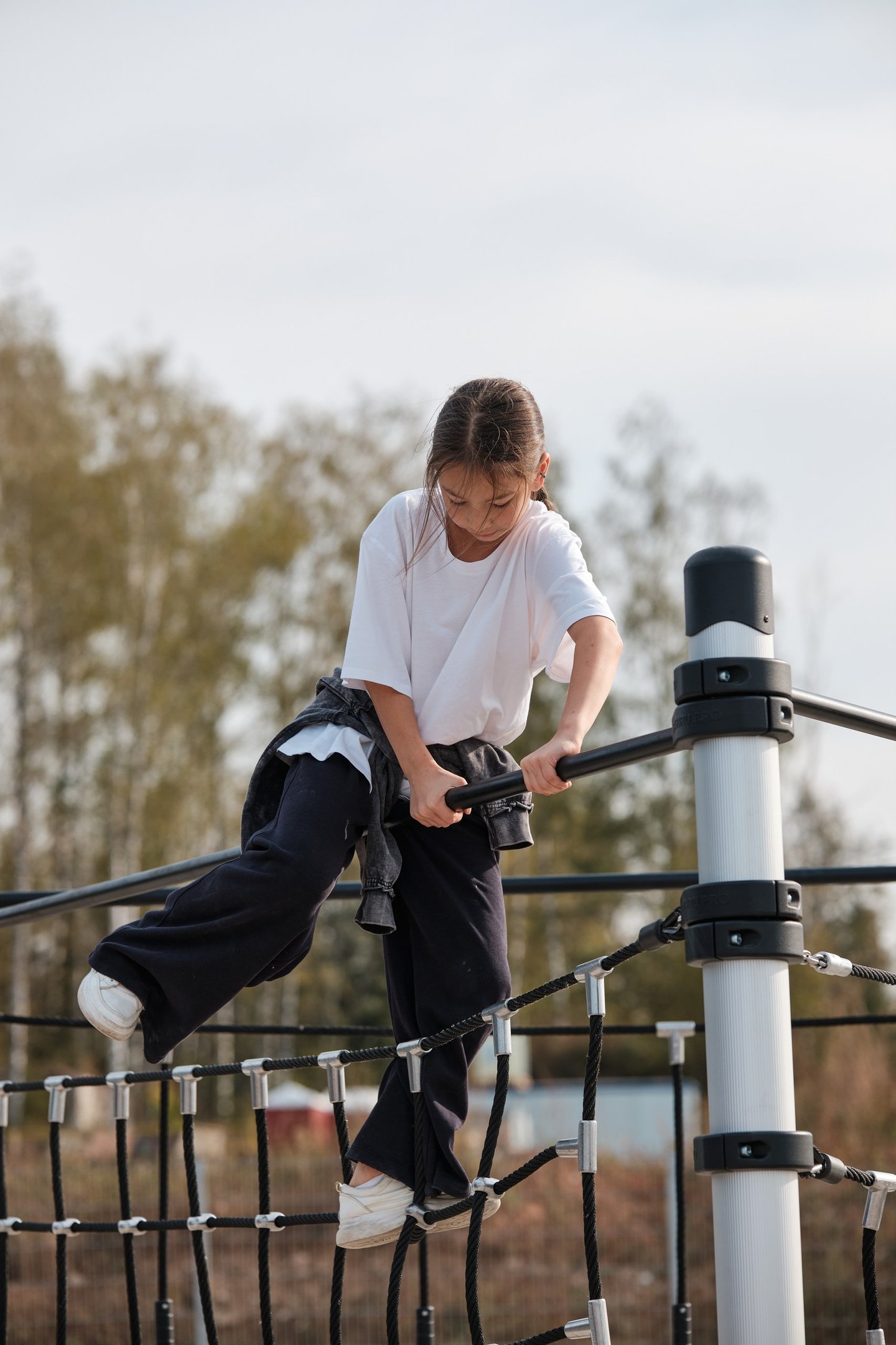 Fille grimpant sur une structure Kenguru Pro Kids Active Play en extérieur.