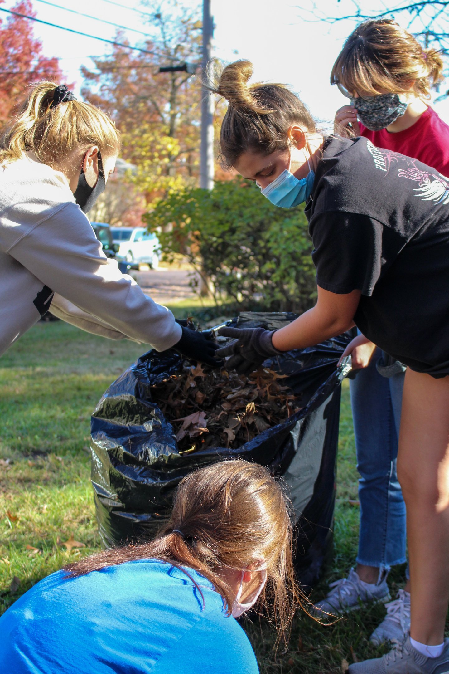 Group of young adult volunteers bagging leaves.