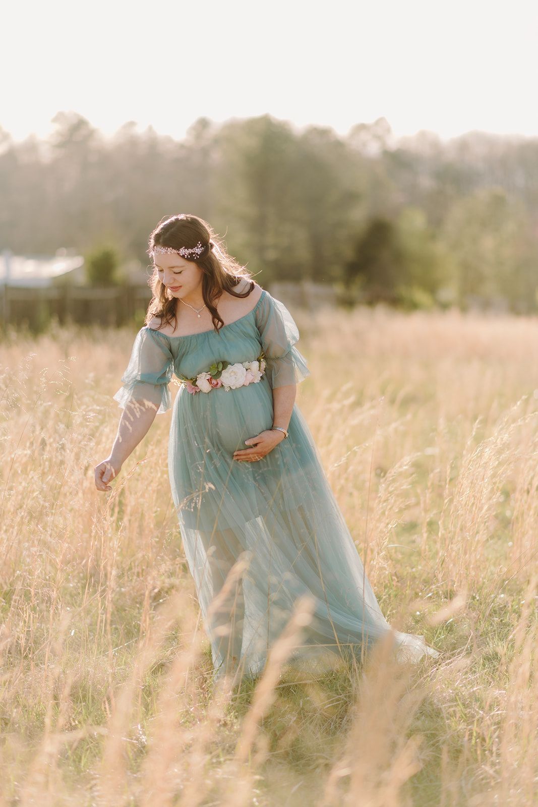 a pregnant woman in a blue dress standing in a field