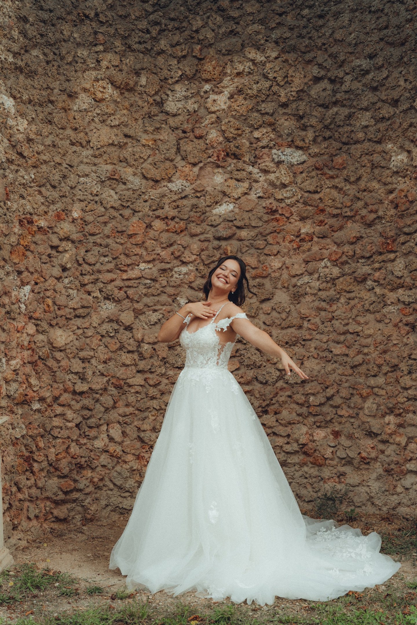 a woman in a wedding dress standing in front of a stone wall
