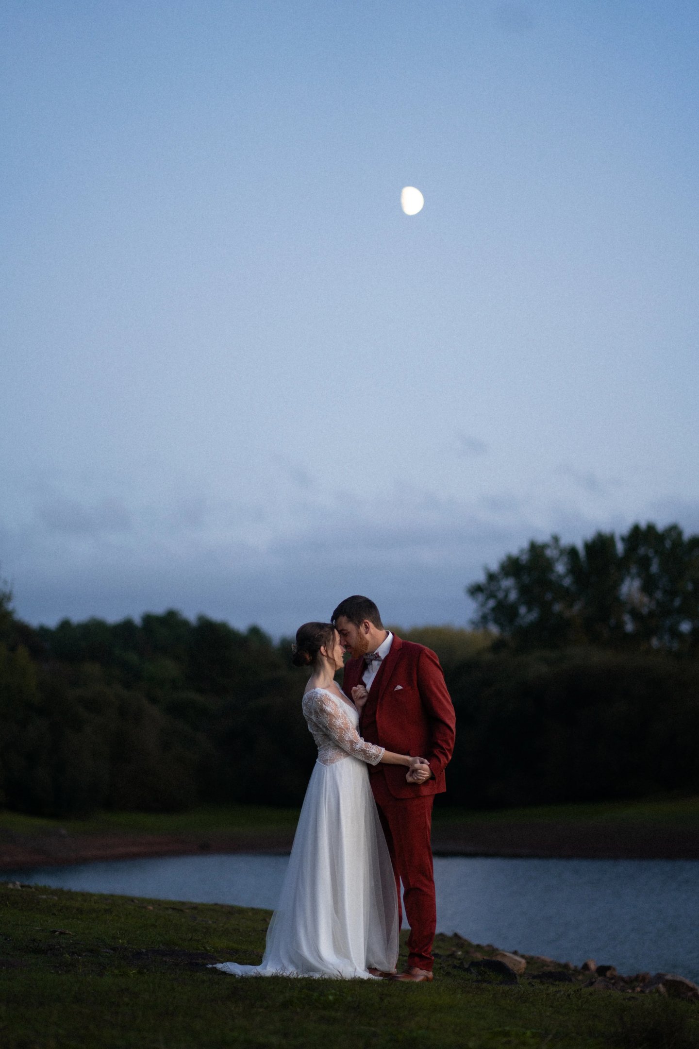un couple face à face près de l'eau la nuit lors de leurs photos de mariage à Guignen, à Rennes