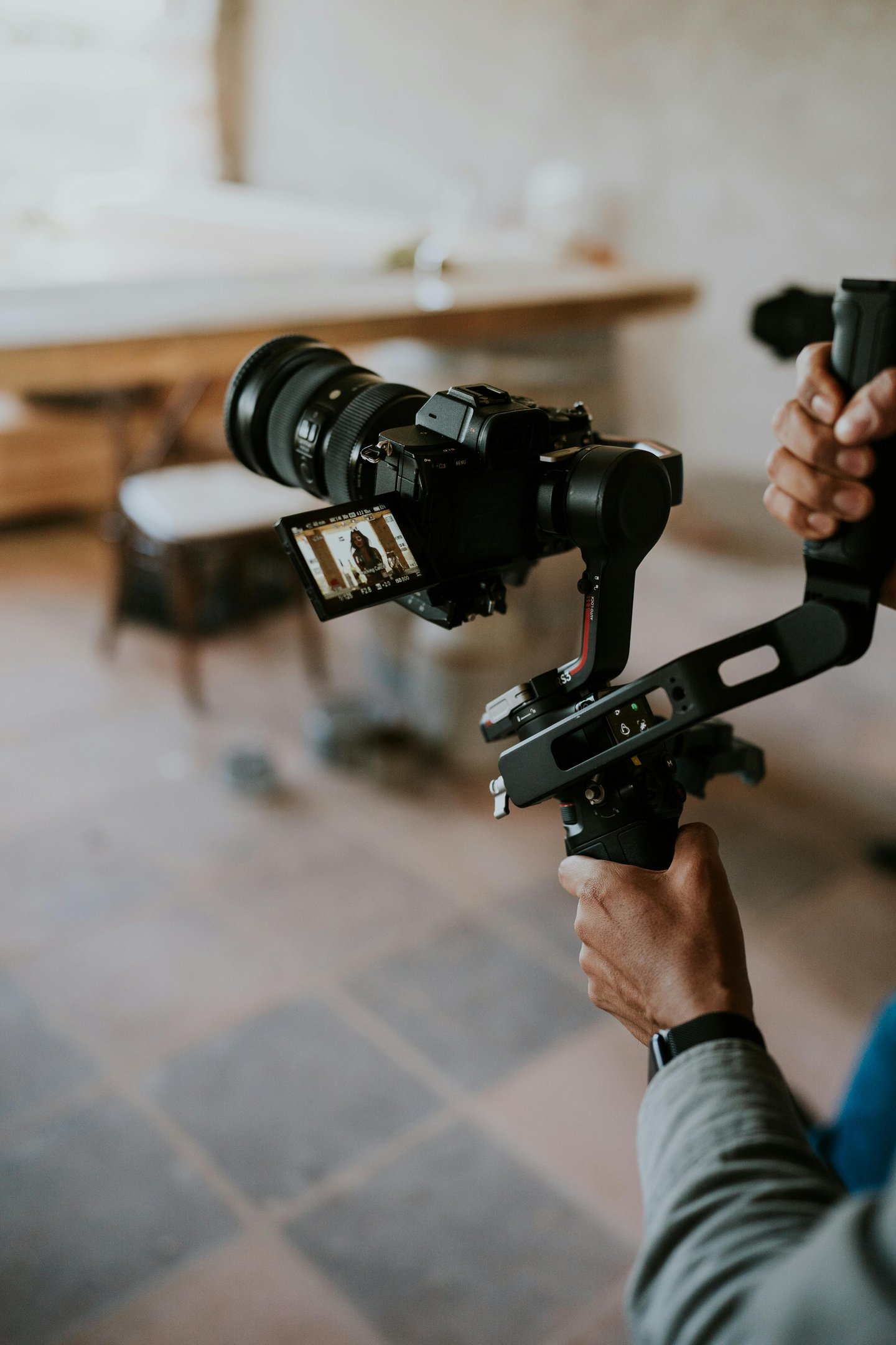 A videographer uses a professional gimbal stabilizer and mirrorless camera for video production.