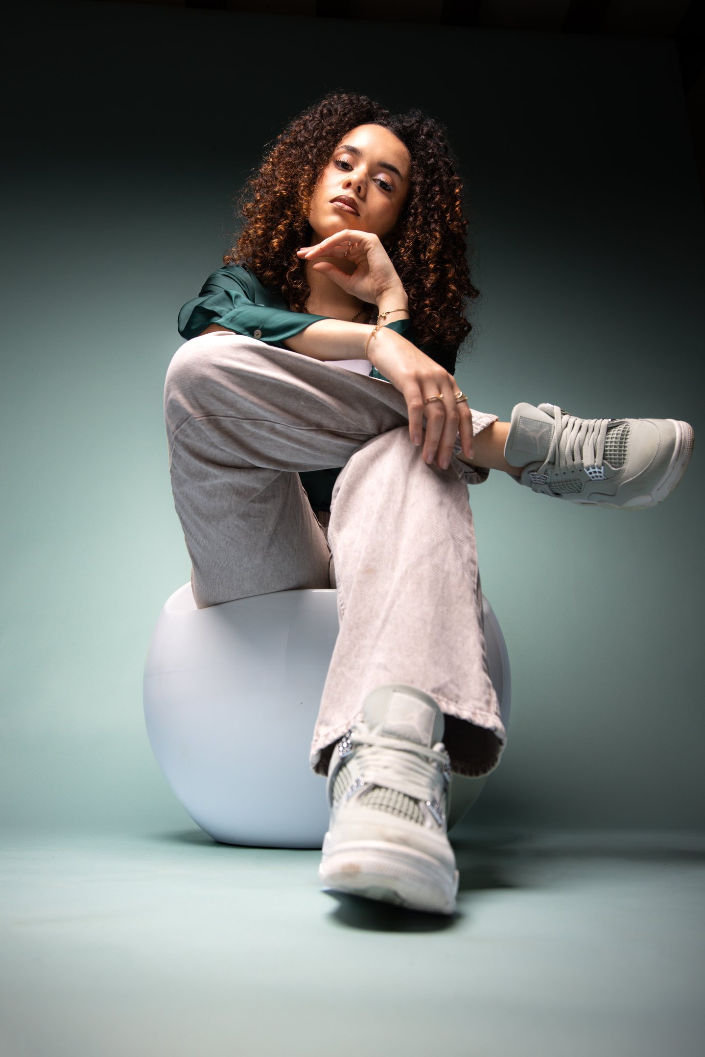 Young woman with curly hair wearing gray Nike Air Jordan sneakers and corduroy pants.