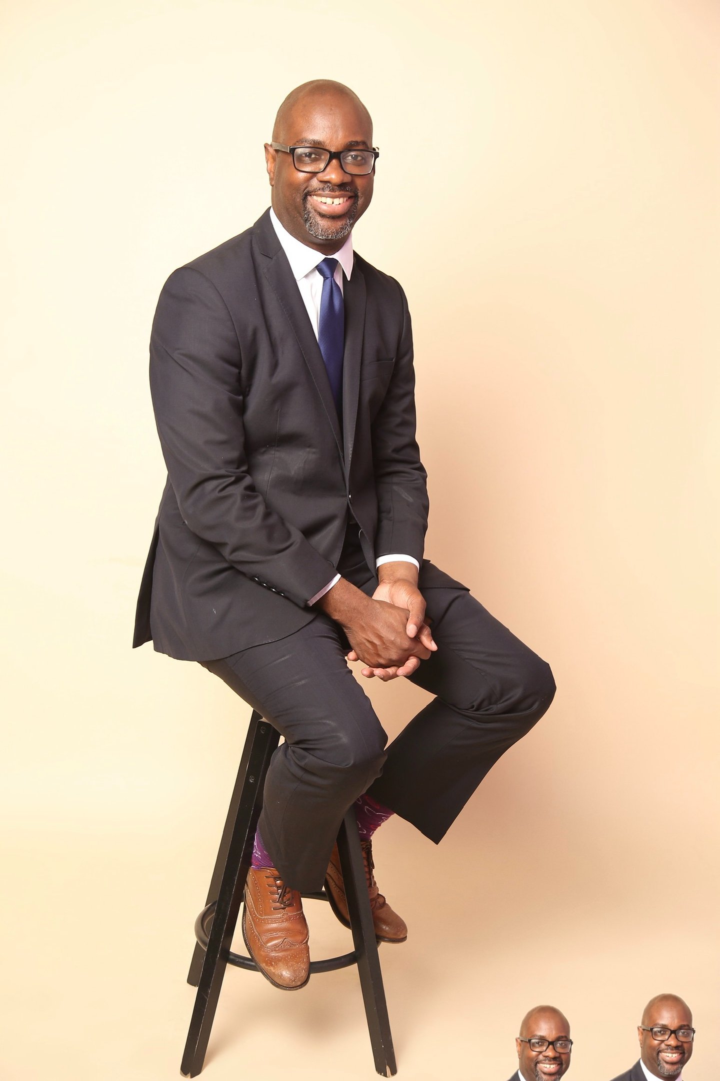 a man in a suit and tie sitting on a stool