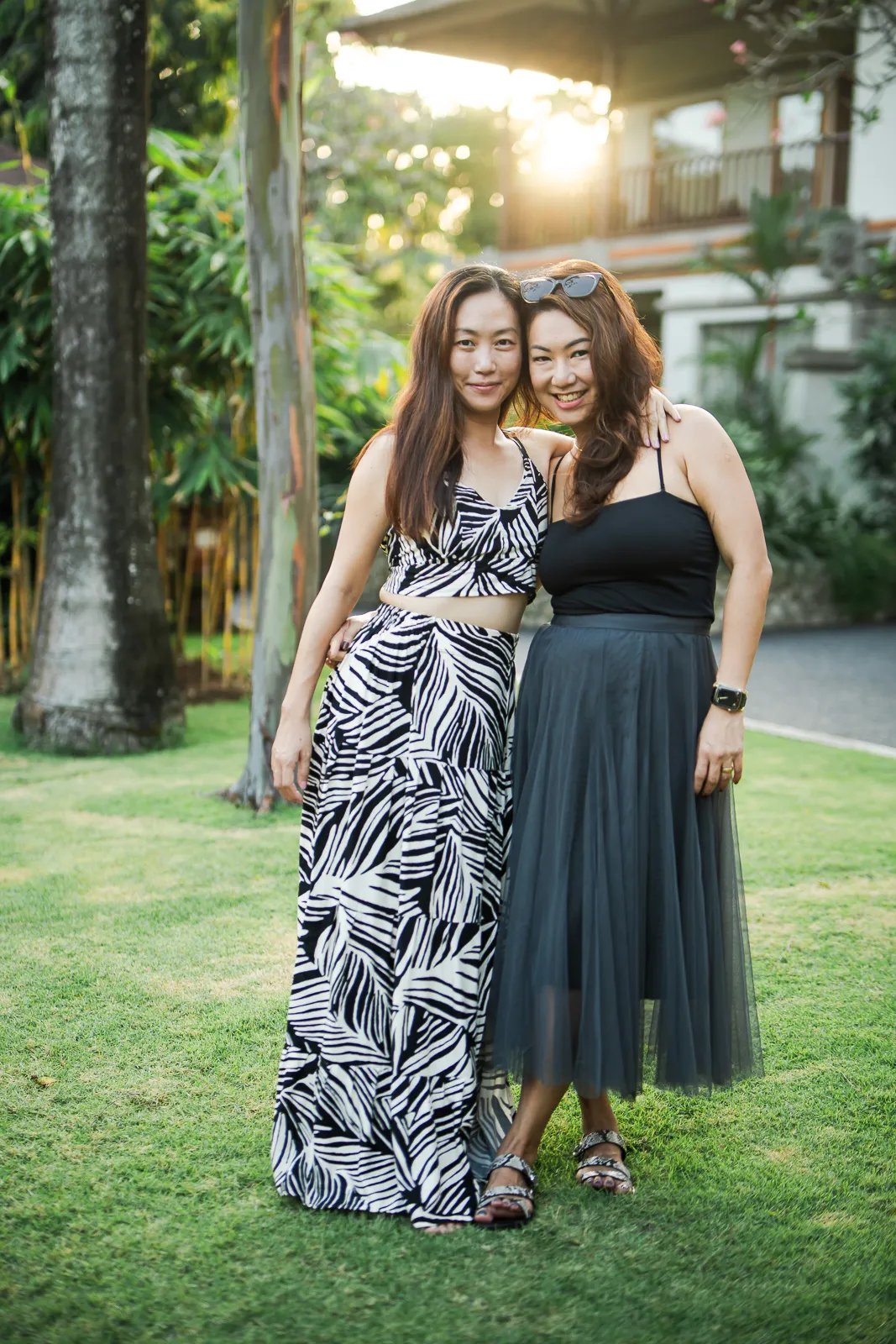 Two women friends during relaxed family photography session at Padma Resort Legian Bali garden.
