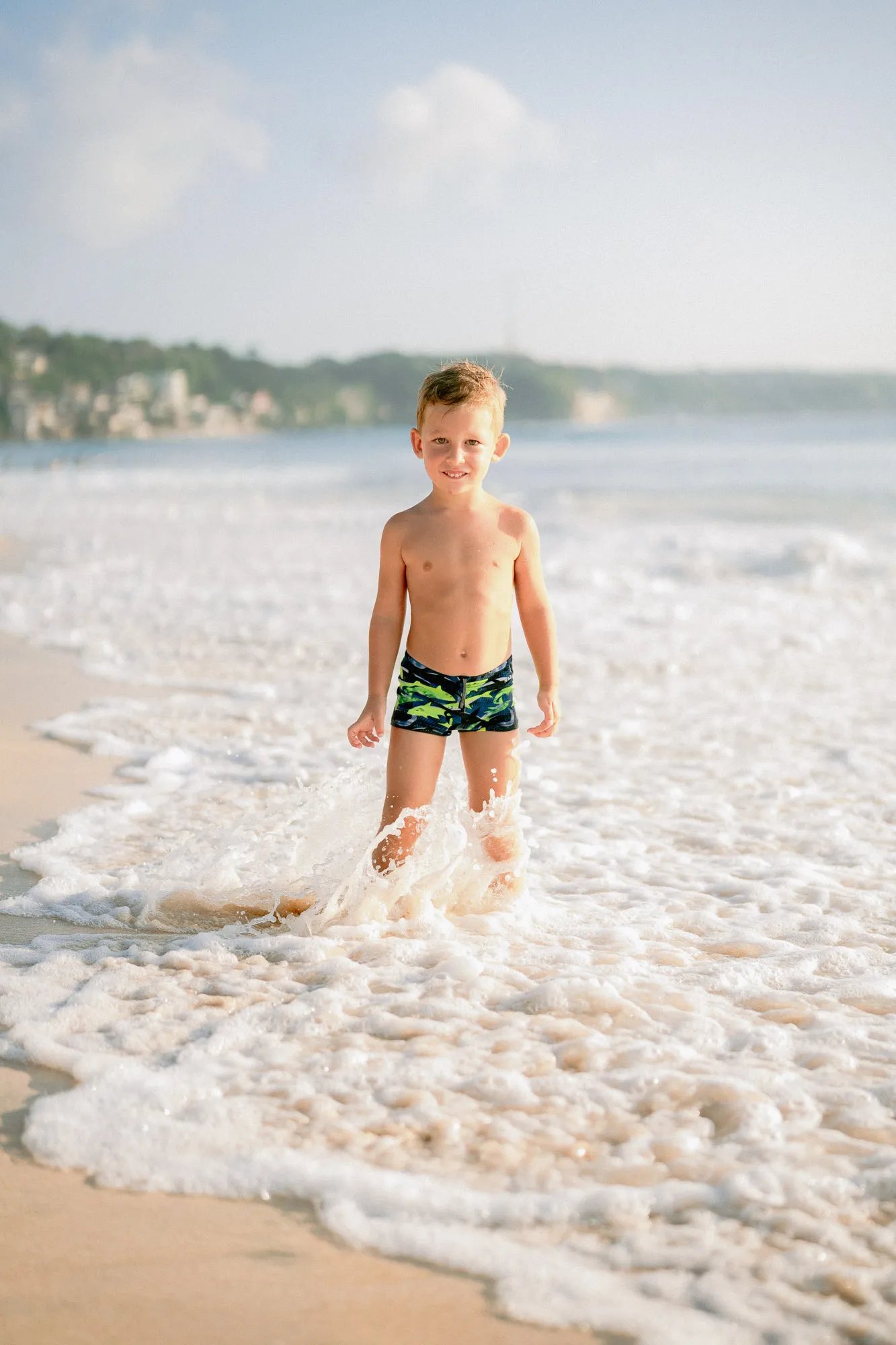 Young boy enjoying the ocean waves during a family photography session at Dreamland Beach Bali.