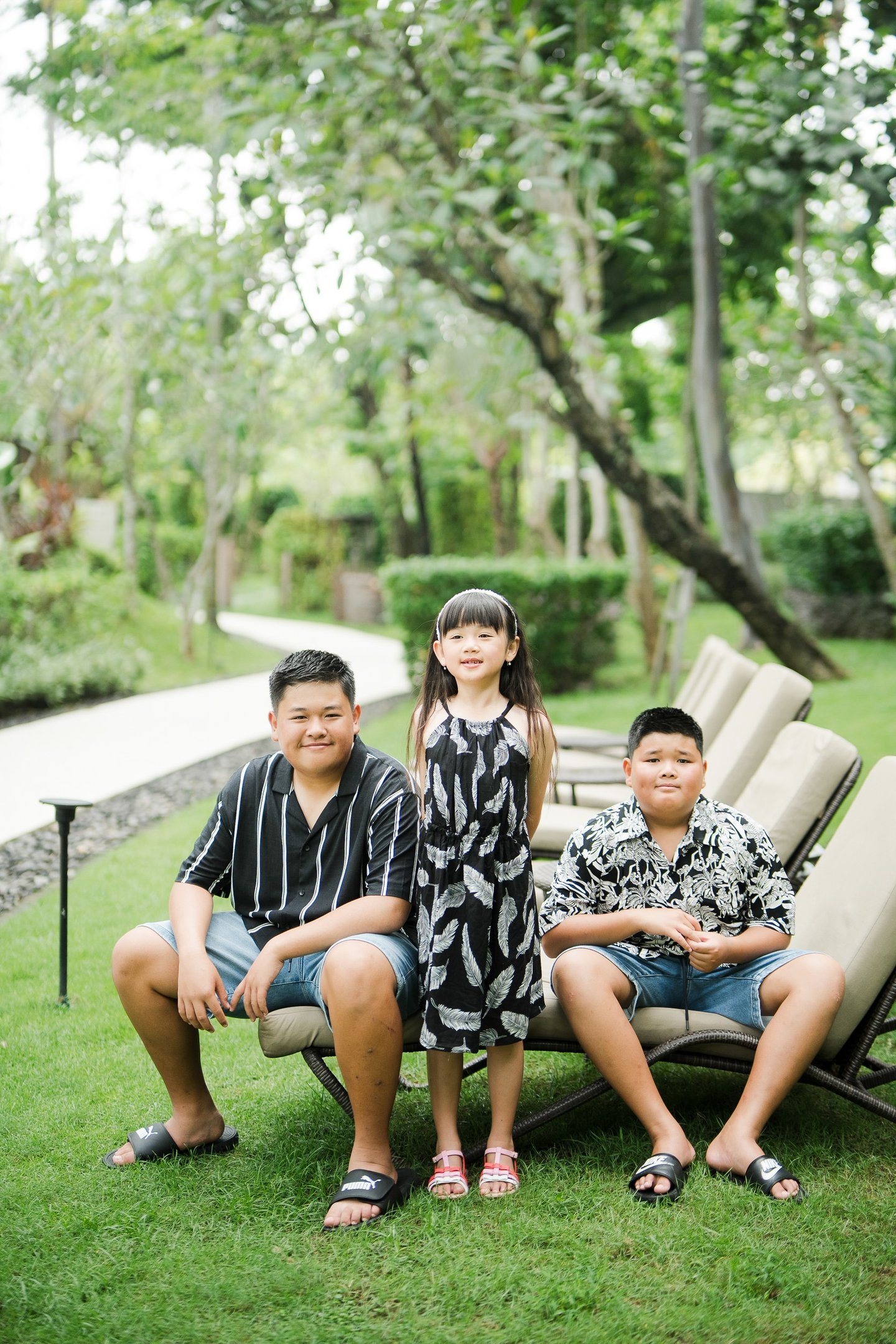 family sitting together on a garden lawn during a relaxed family photography session at Movenpick Jimbaran Bali