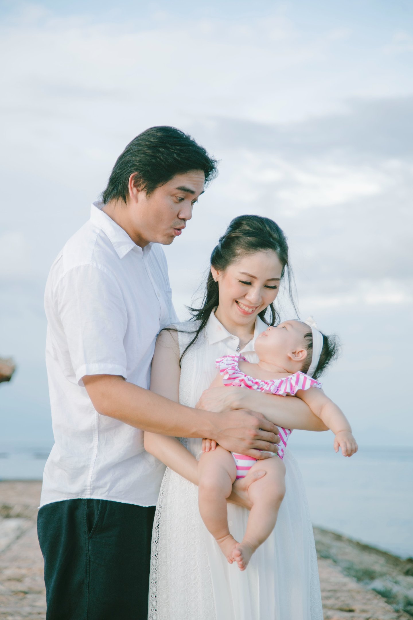 Parents holding baby with ocean view during family photography session at Sofitel Nusa Dua Bali