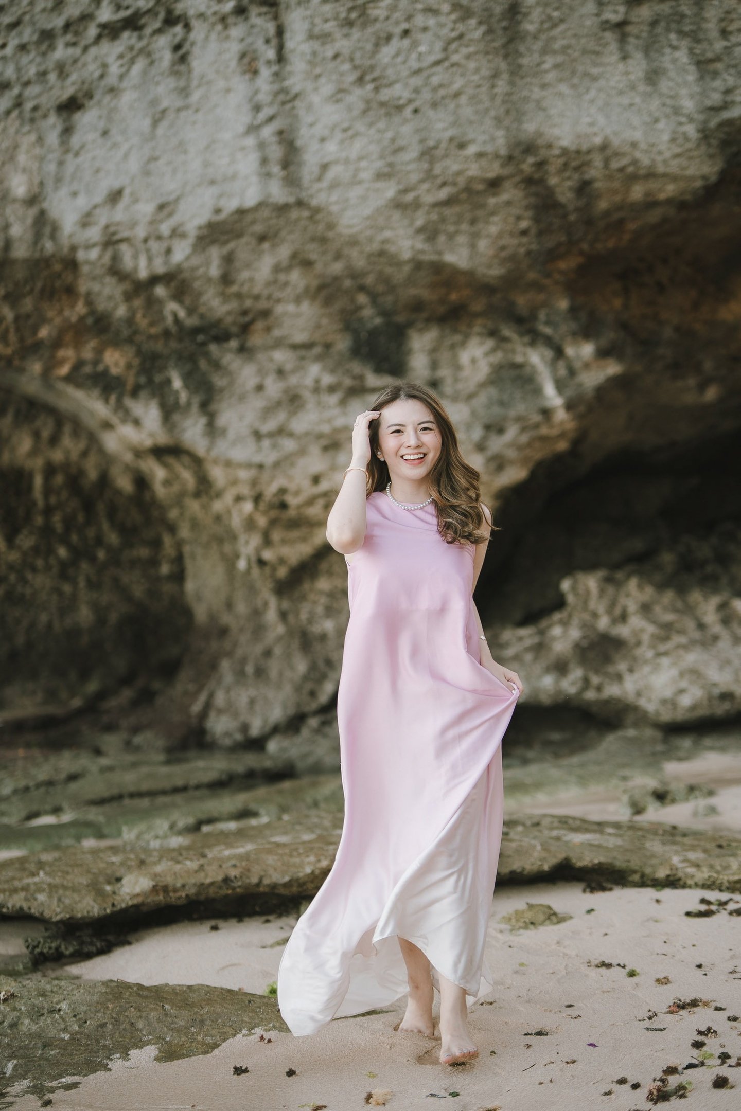 Woman walking along the beach near cliff during photoshoot at Geger Beach Nusa Dua Bali