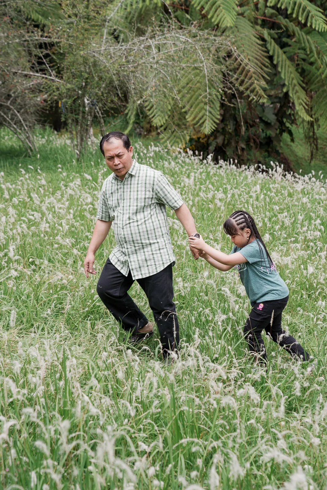 Iqbal family walking together in an open grass field at Kebun Raya Bedugul Bali.