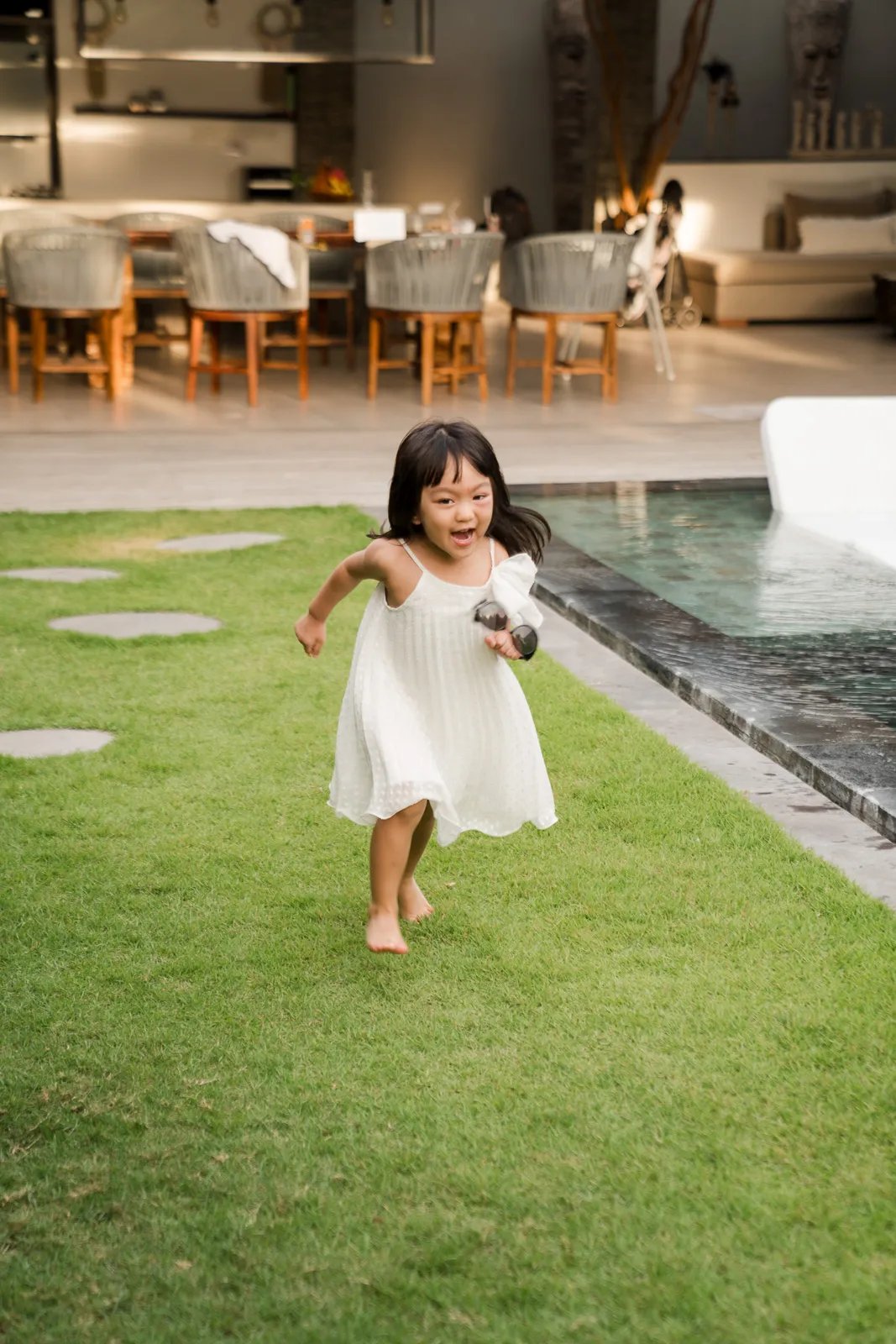 Candid lifestyle photograph of a little girl running through a tropical private villa in Seminyak Bali