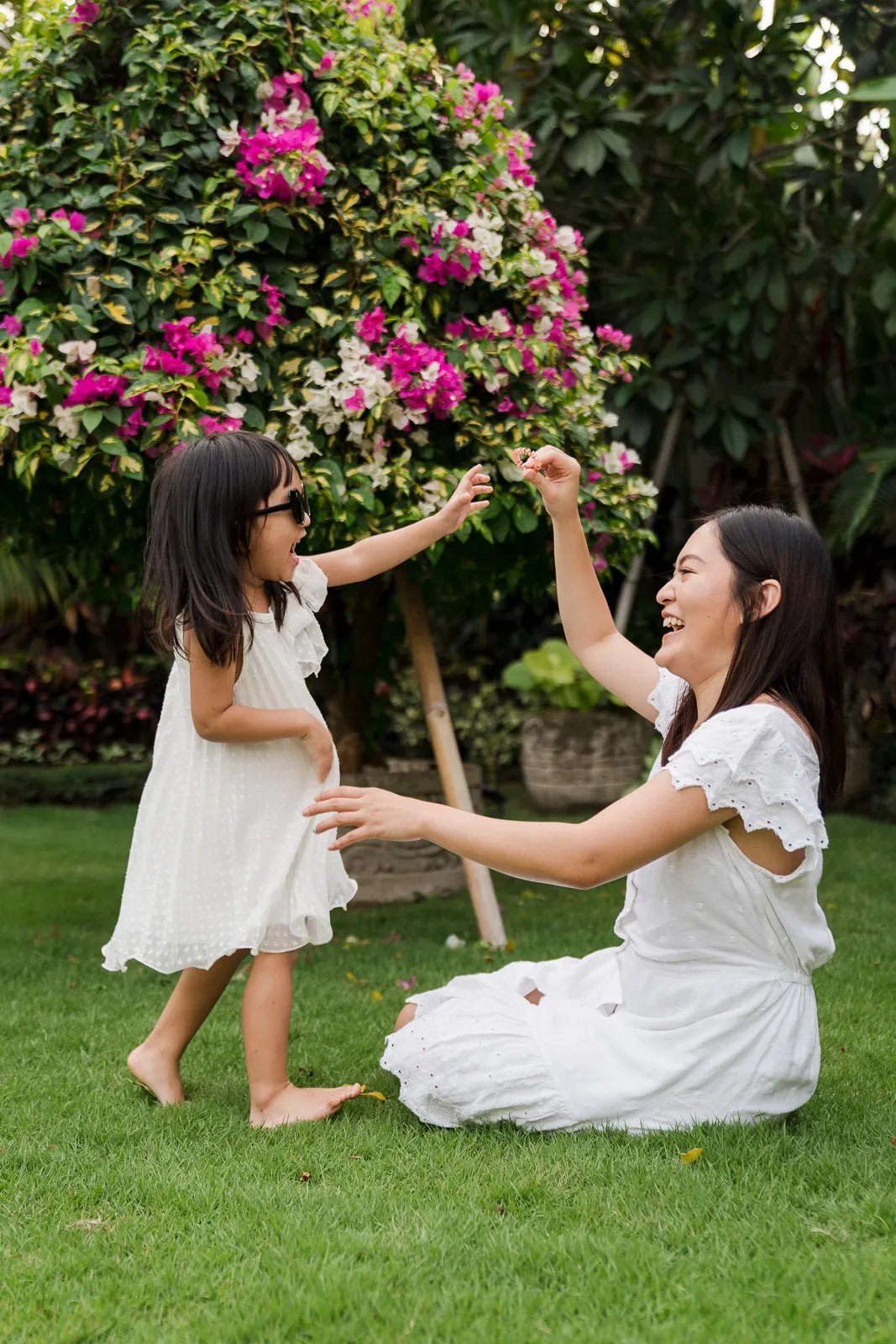 Candid portrait of sisters playing together outdoors during a natural family photography session at a private villa in Bali.