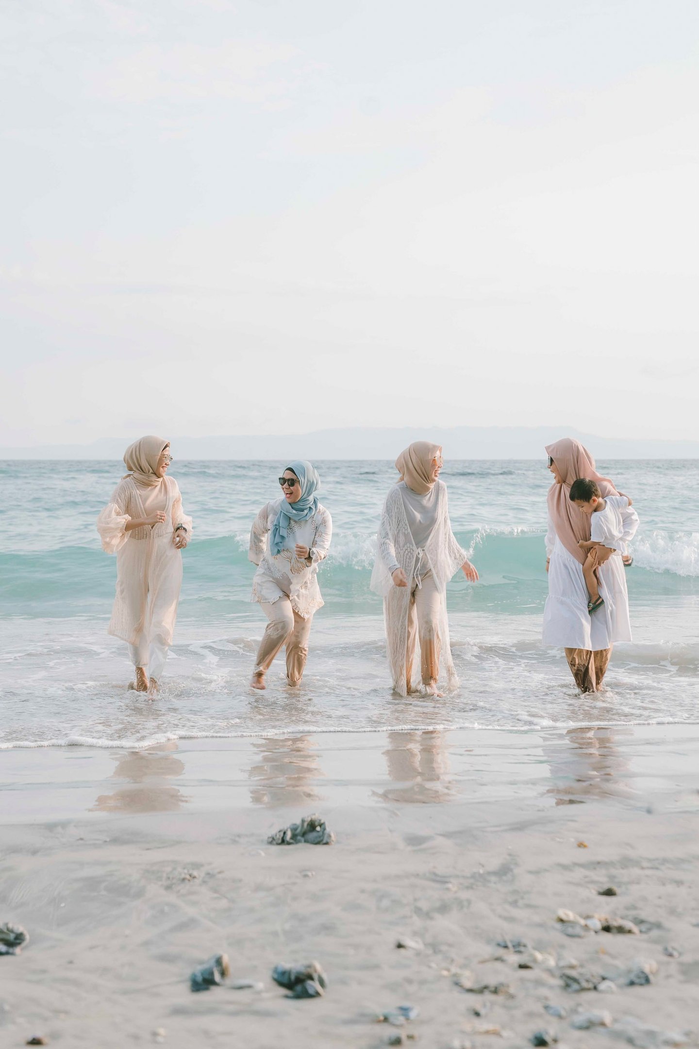 Group of friends walking along the shoreline during photoshoot at Candi Beach Resort Karangasem Bali