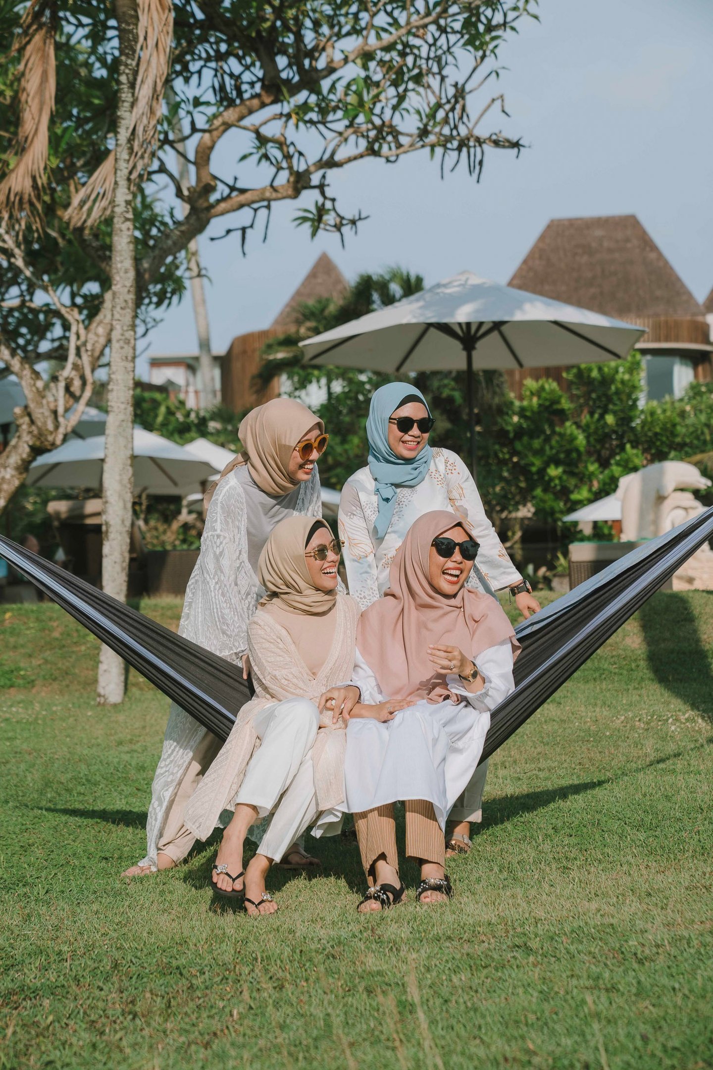Friends sitting together on hammock during photoshoot at Candi Beach Resort Karangasem Bali