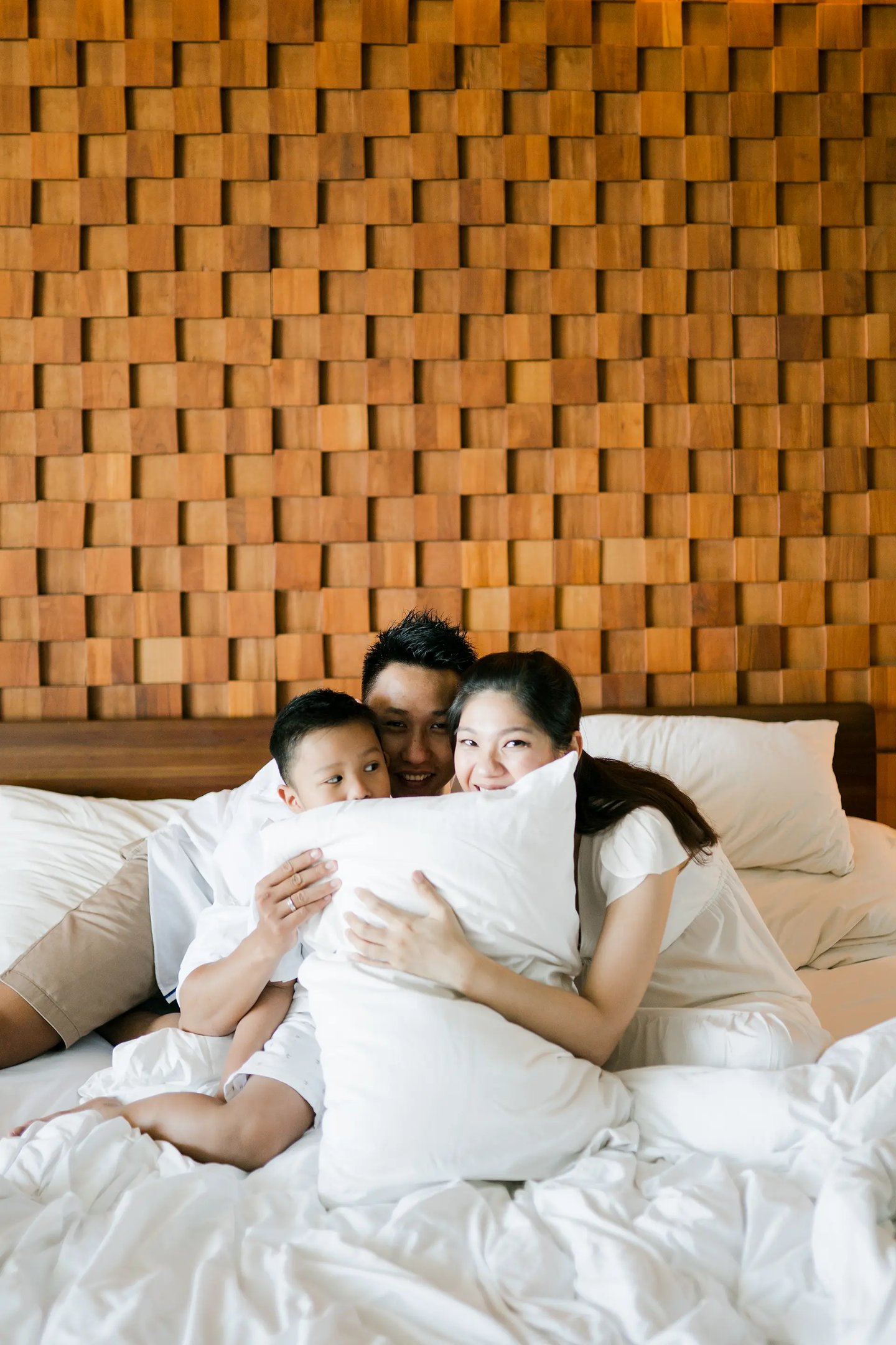 Family cuddling together on the bed during a cozy lifestyle family session at Anantara Uluwatu.