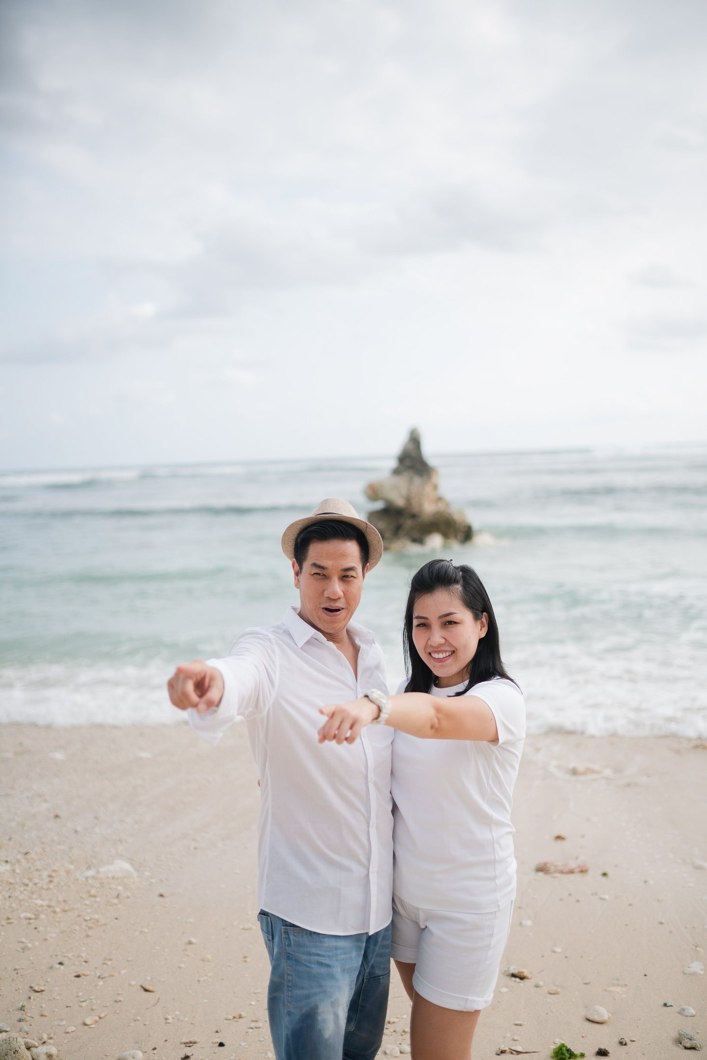 Couple standing together in front of the ocean at Melasti Beach Bali during a relaxed beach portrait session