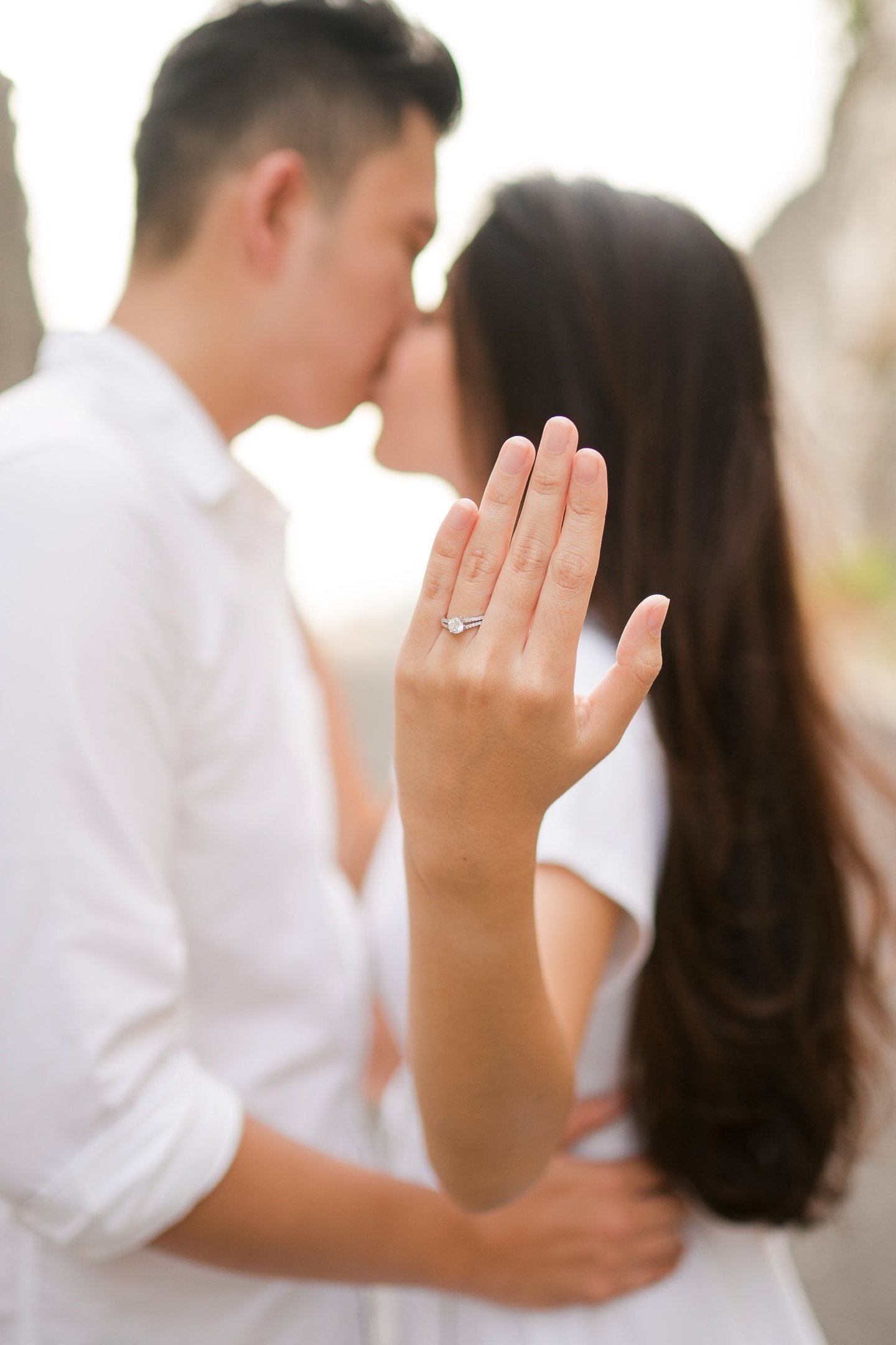 Couple kissing while showing engagement ring during proposal at Melasti Beach Bali  
