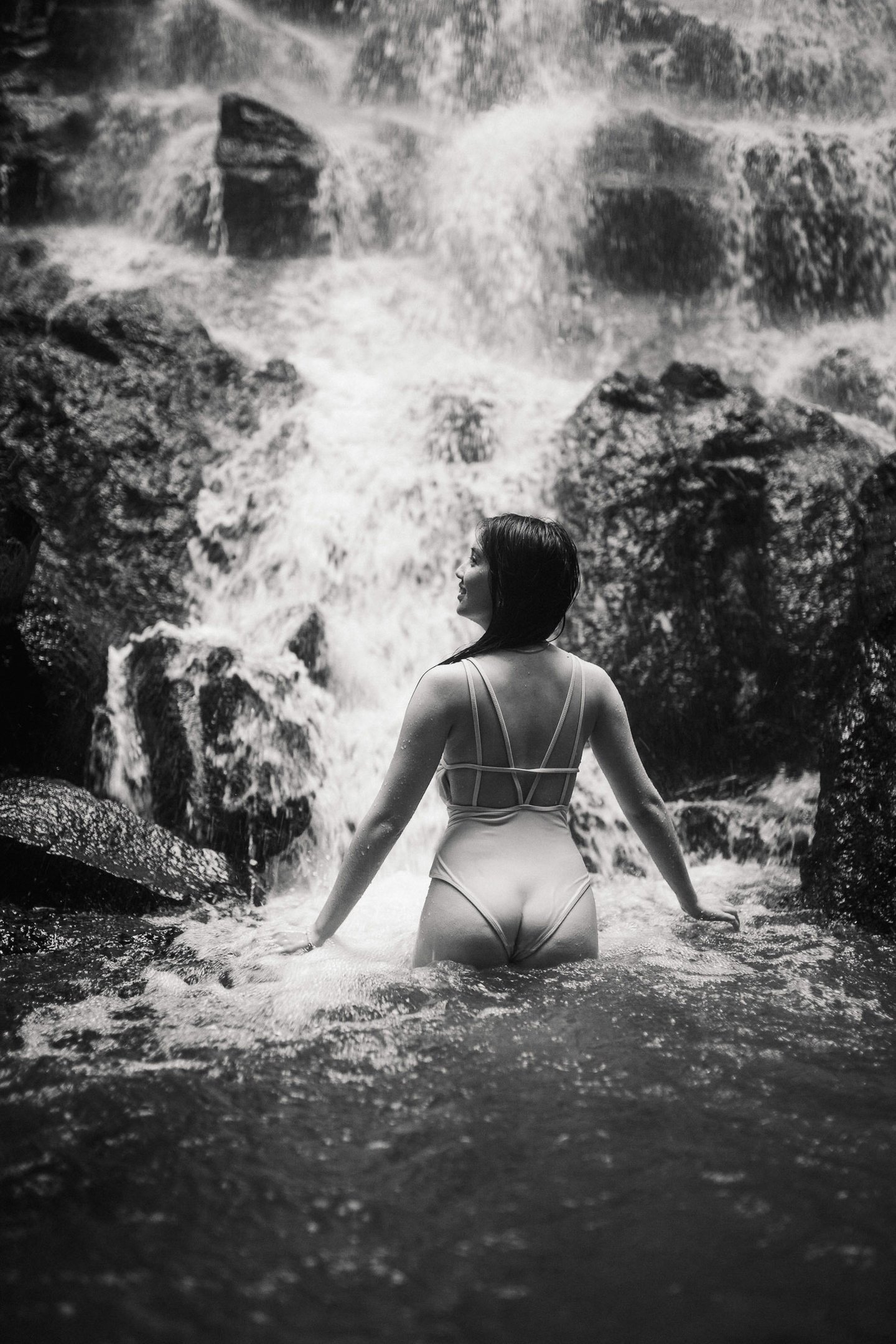 Back view portrait of woman standing under waterfall at Kanto Lampo Bali