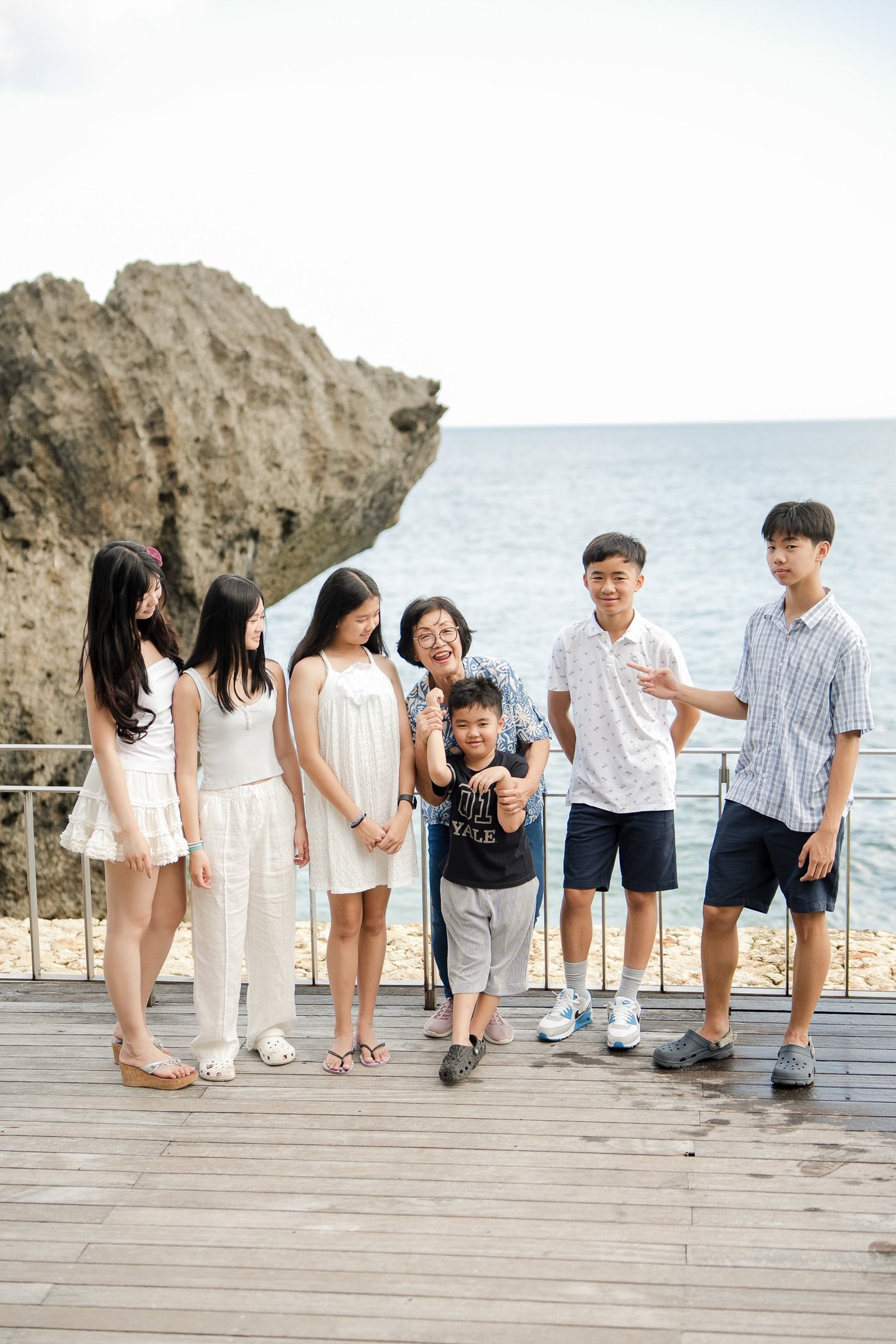 Extended family standing together by the ocean during a natural lifestyle photography session at Ayana Jimbaran Bali