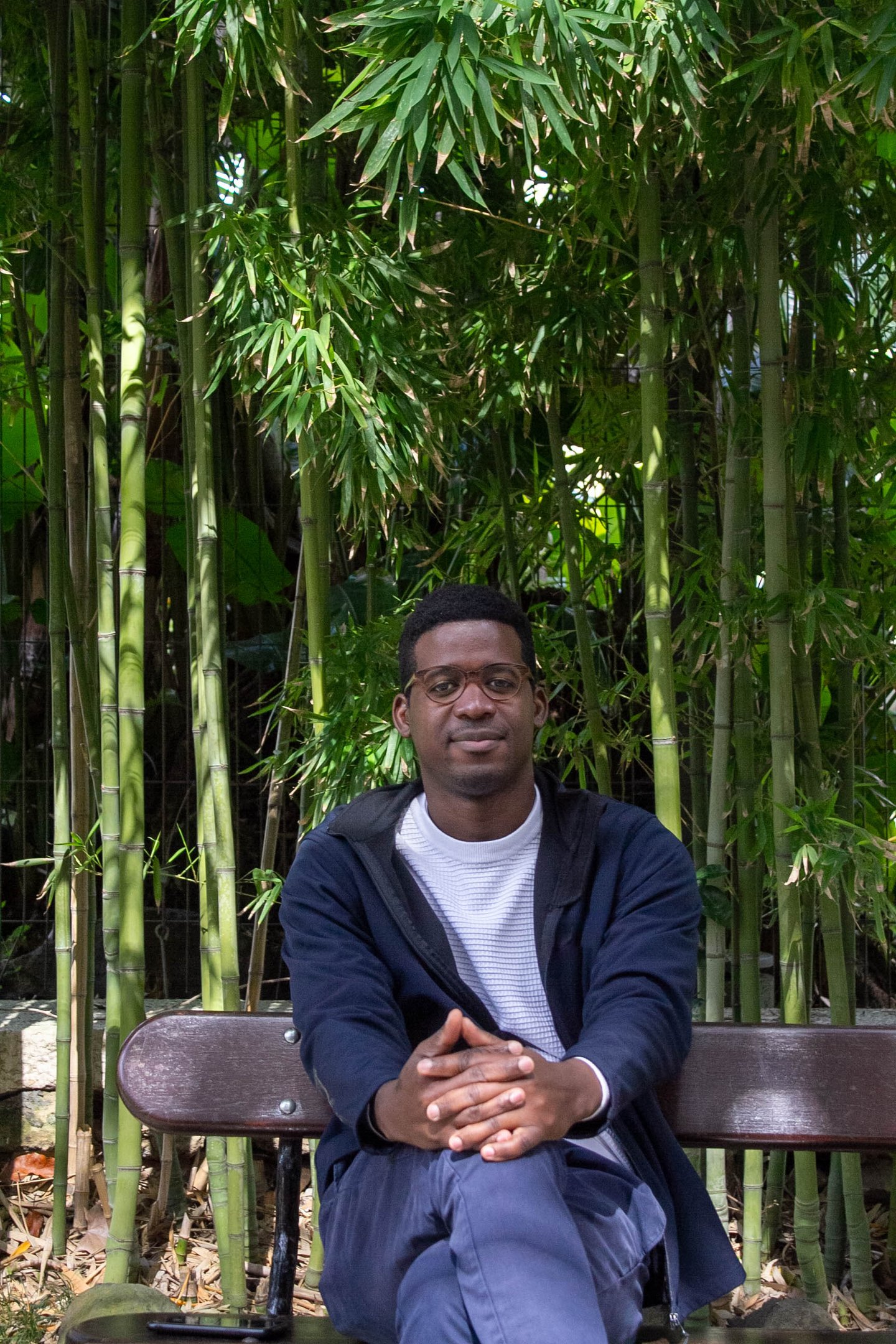 man  with glasses sitting in front of bamboo 