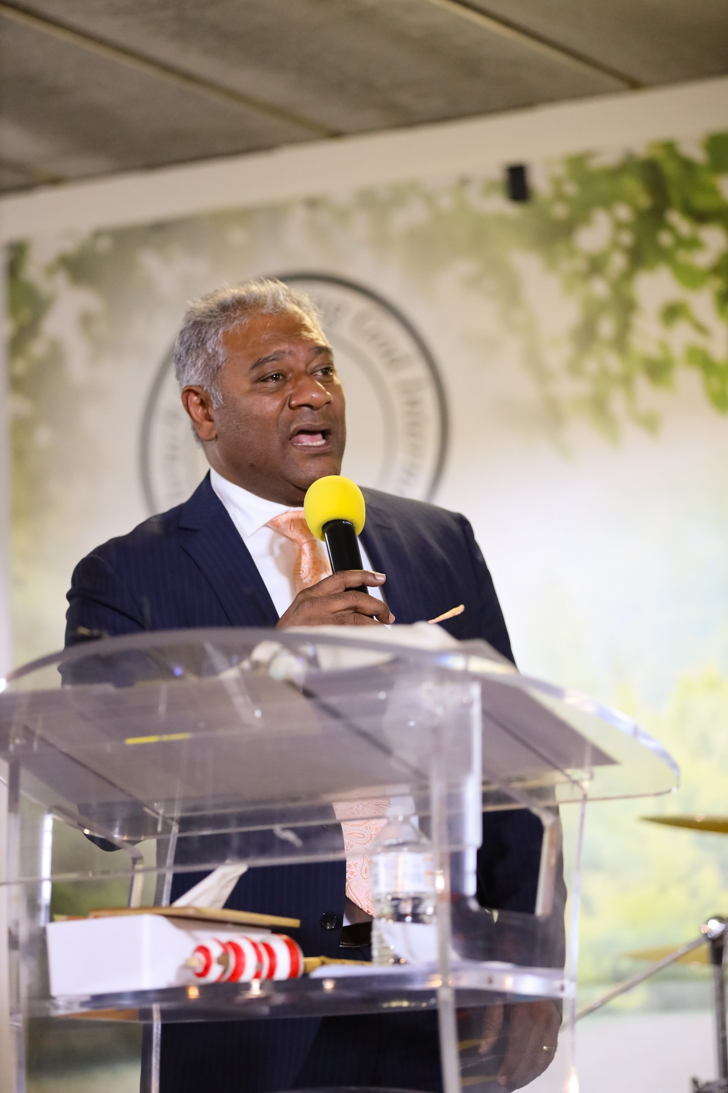 Male holding a microphone wearing tie and suit 