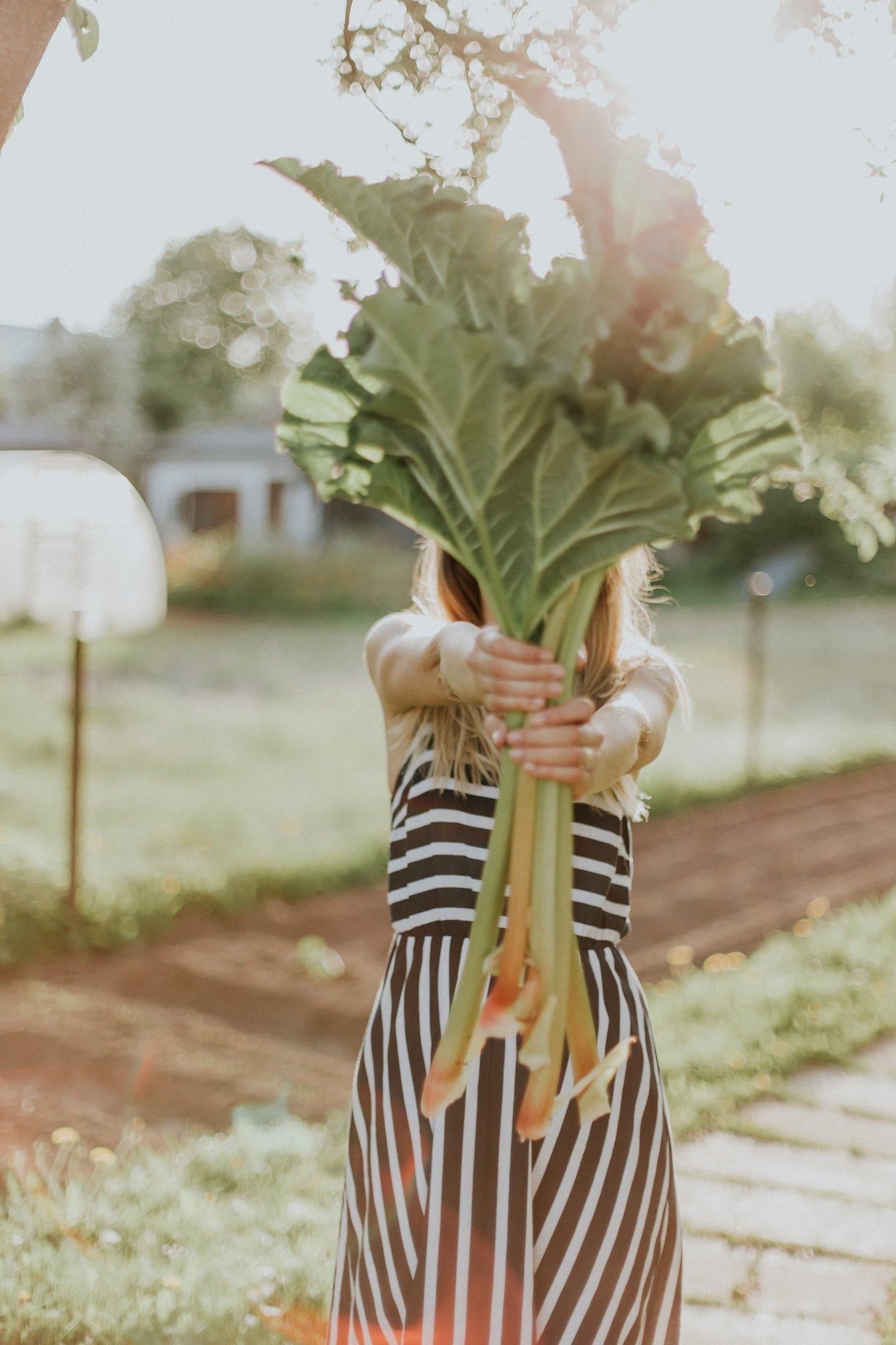 a woman holding a bunch of green leafy vegetables in her outstretched hands