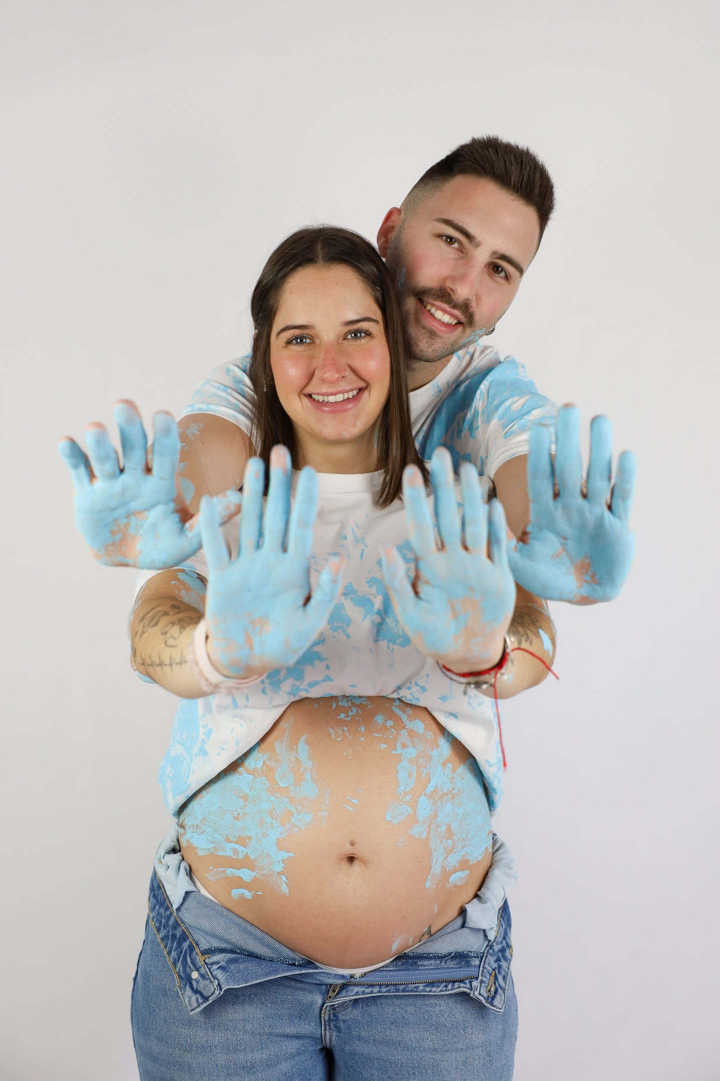 Sessió de fotos de gender reveal a Girona d'una parella amb pintura blava en estudi fotogràfic