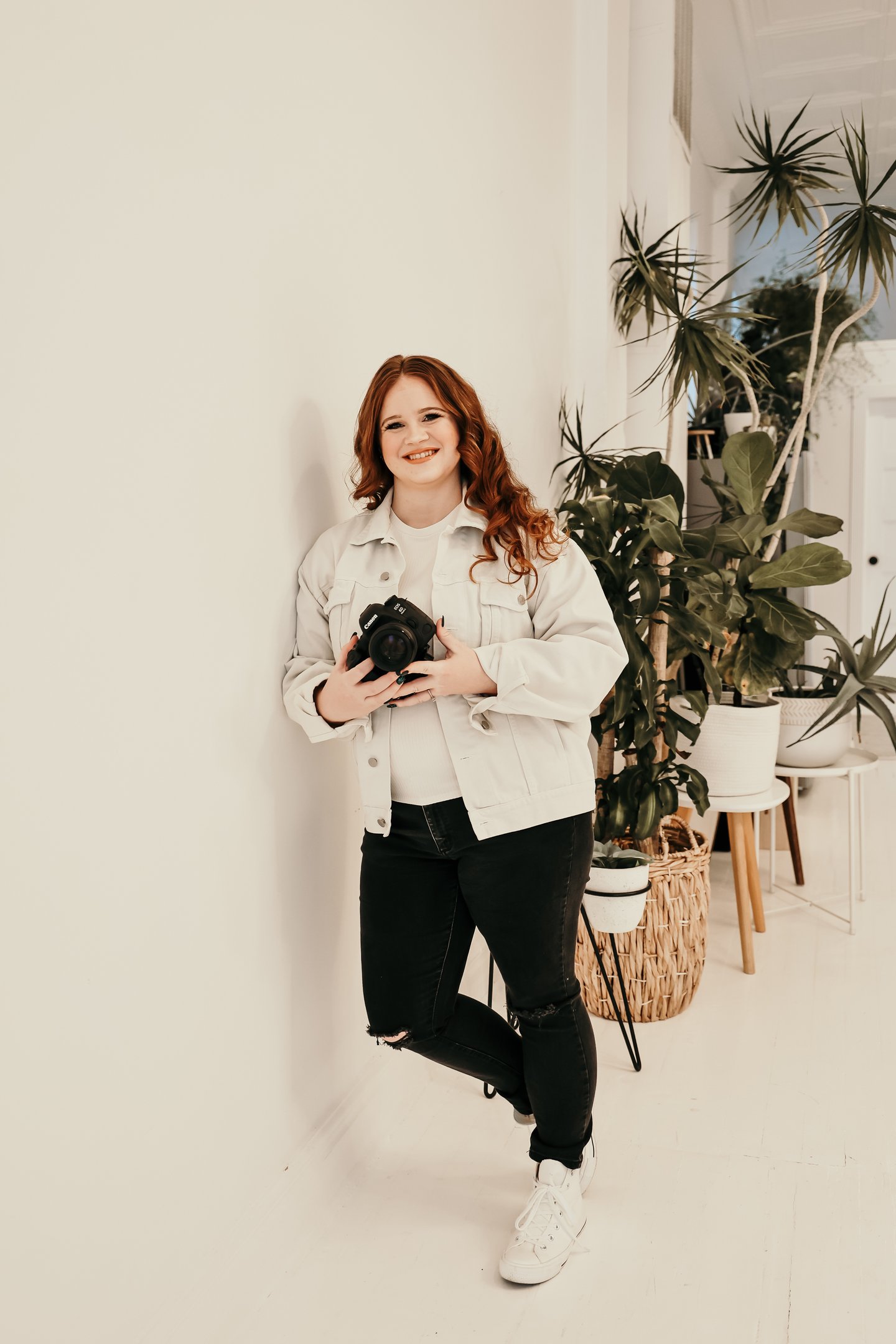Rachel smiling and holding her camera with plants in the background