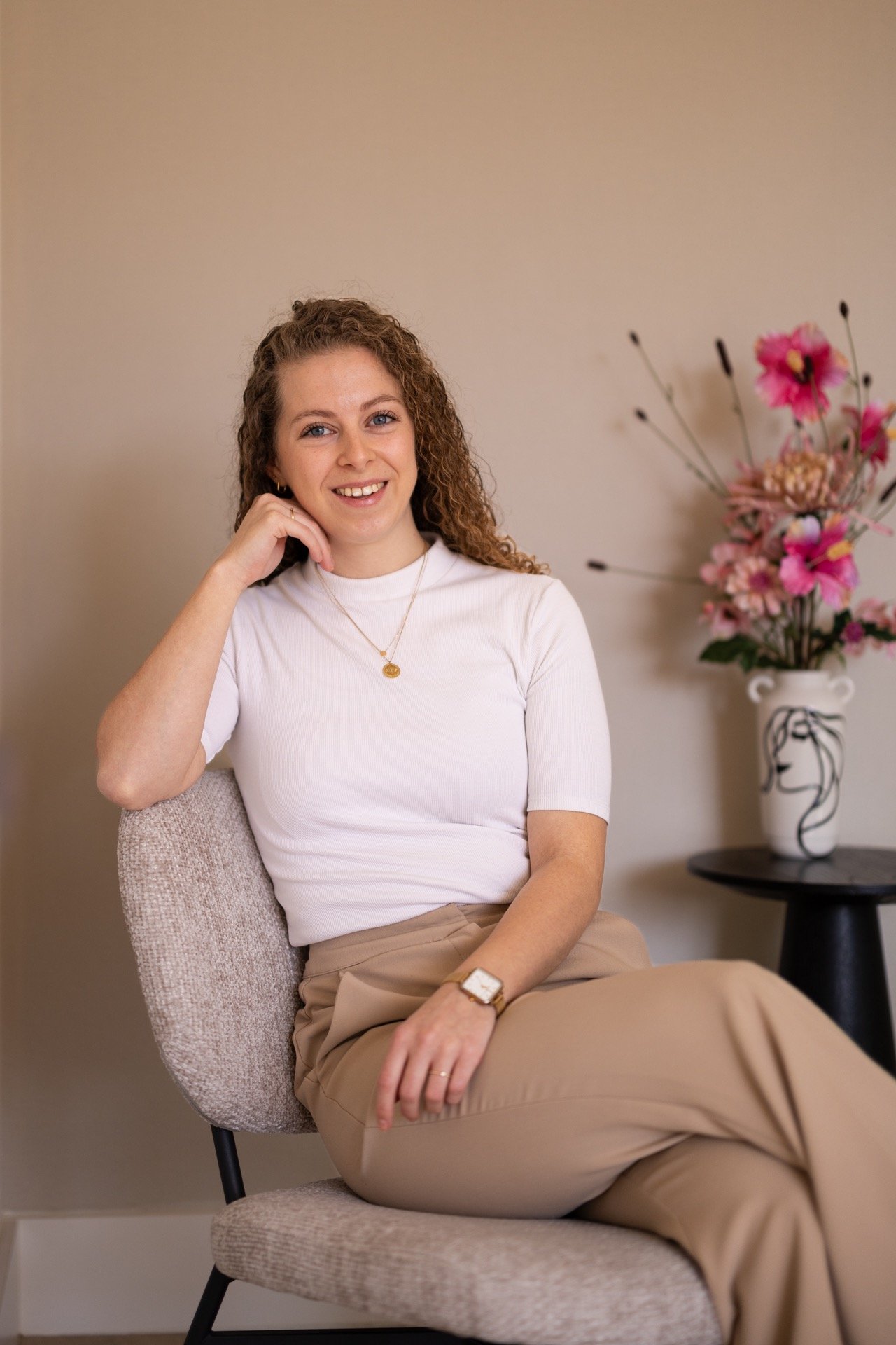a woman, the writher, sitting in a chair with a flower in the background