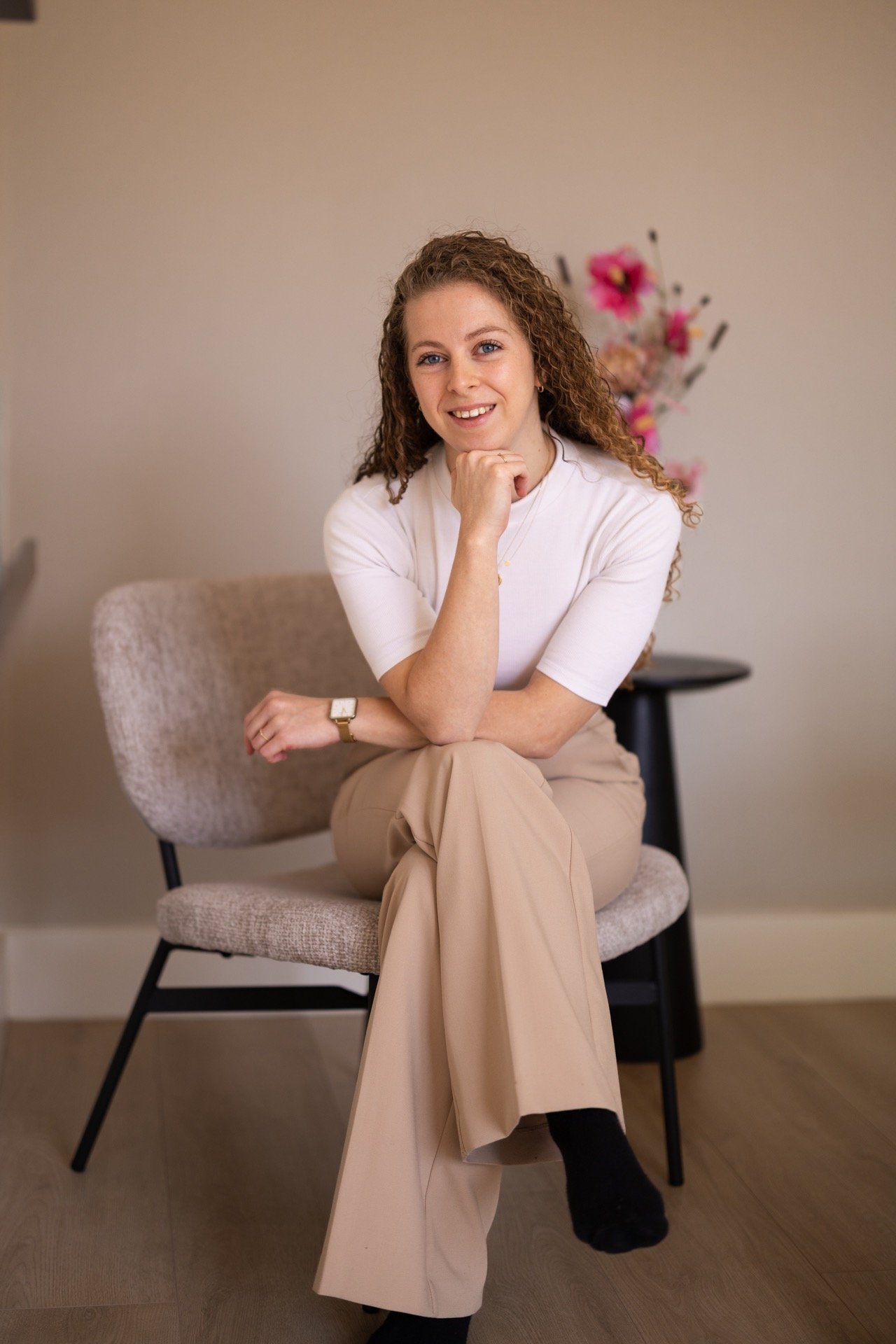 a woman (the owner) sitting in a chair with a flower in the background
