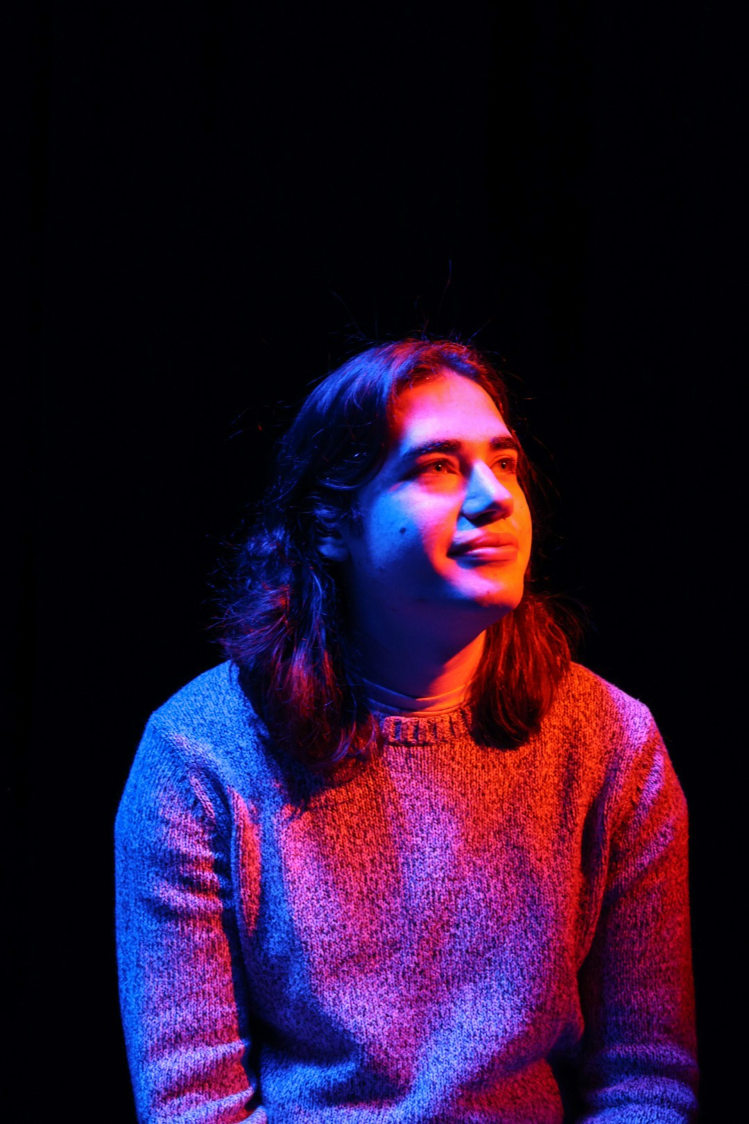 Sam Eads looking up and to the right under orange, blue and purple light