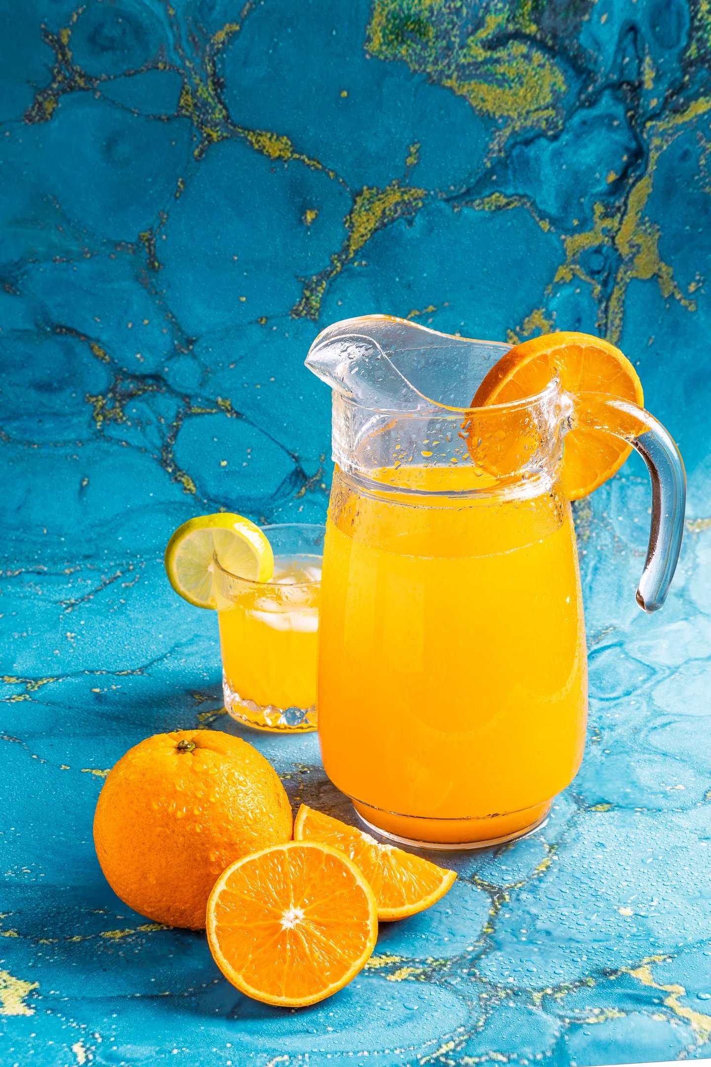a pitcher of orange juice with oranges and lemon
