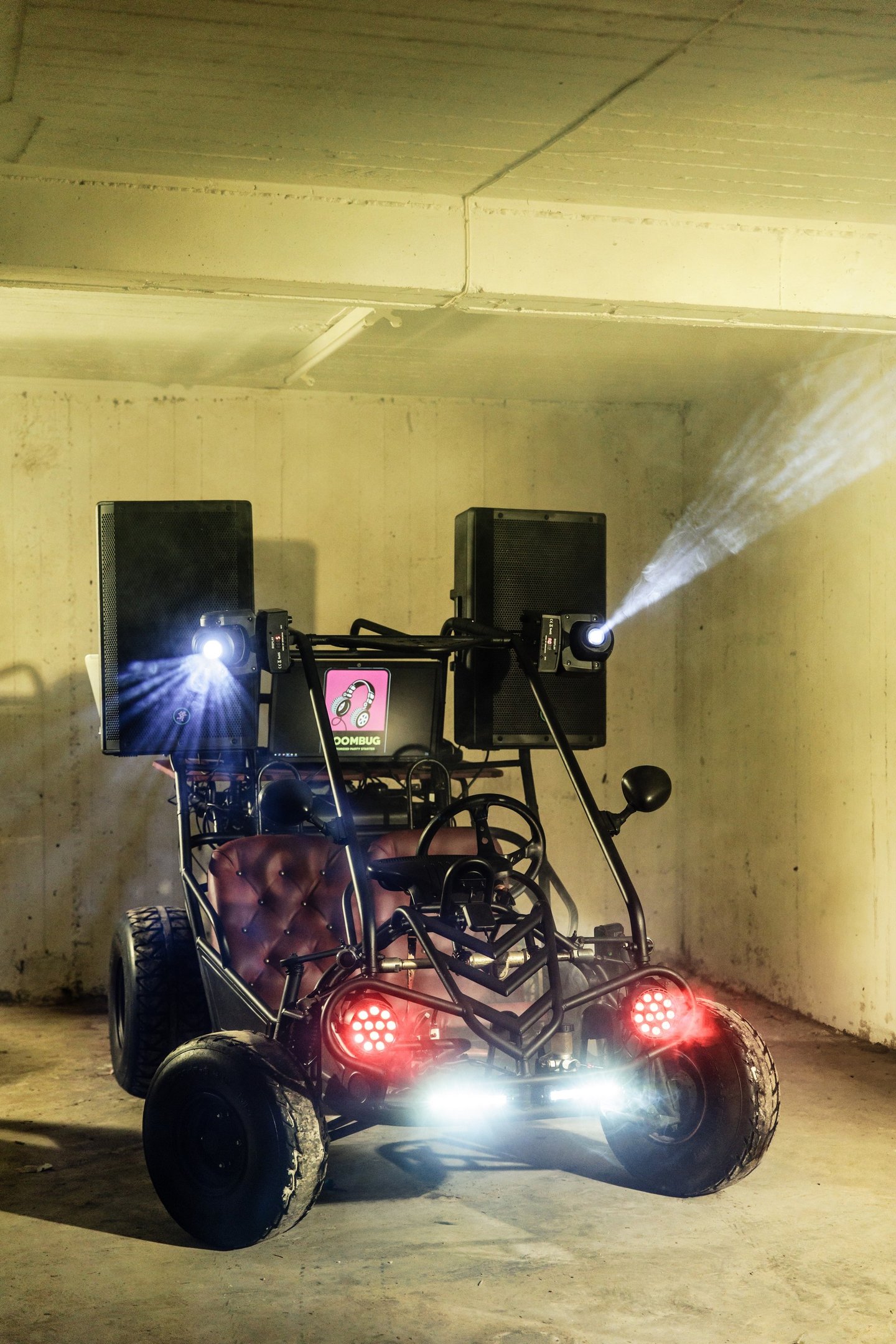 Custom DJ buggy equipped with high-powered speakers, stage lighting, and a mixer in an industrial space.
