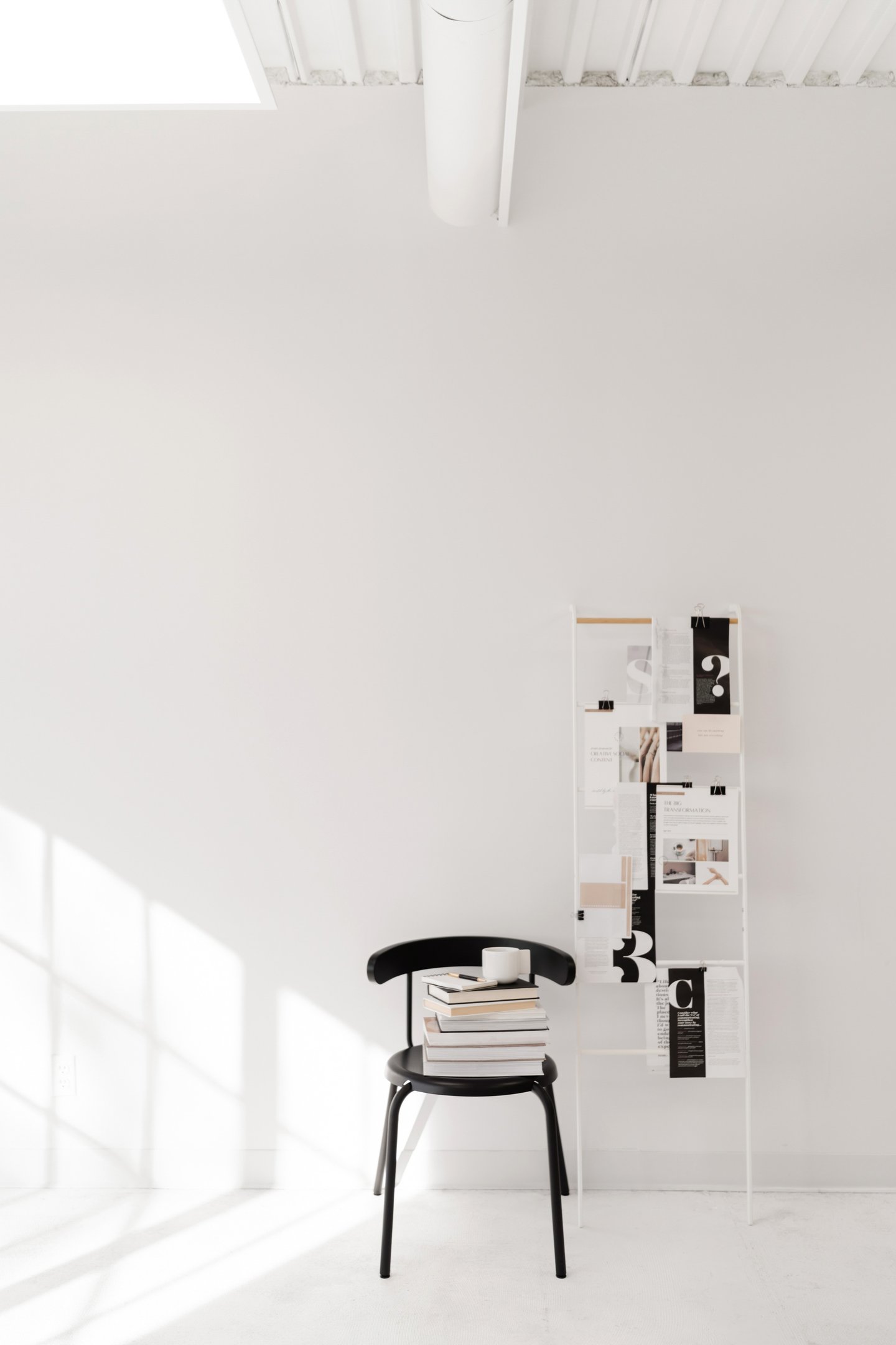 A black chair with a stack of books with a notepad and pen on top.