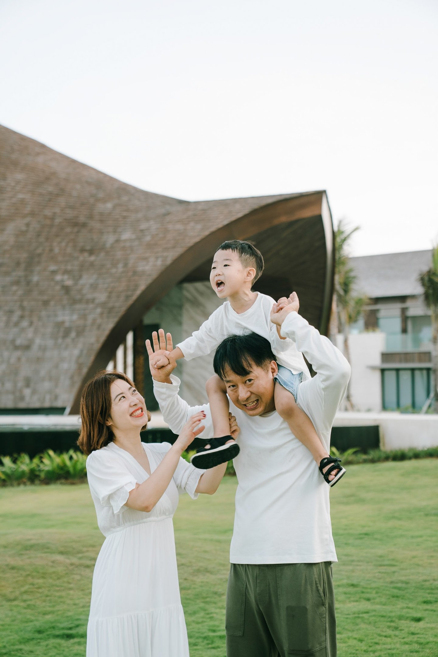 Luxury family photographer in Bali capturing a joyful father lifting his child at The Apurva Kempinski Bali.
