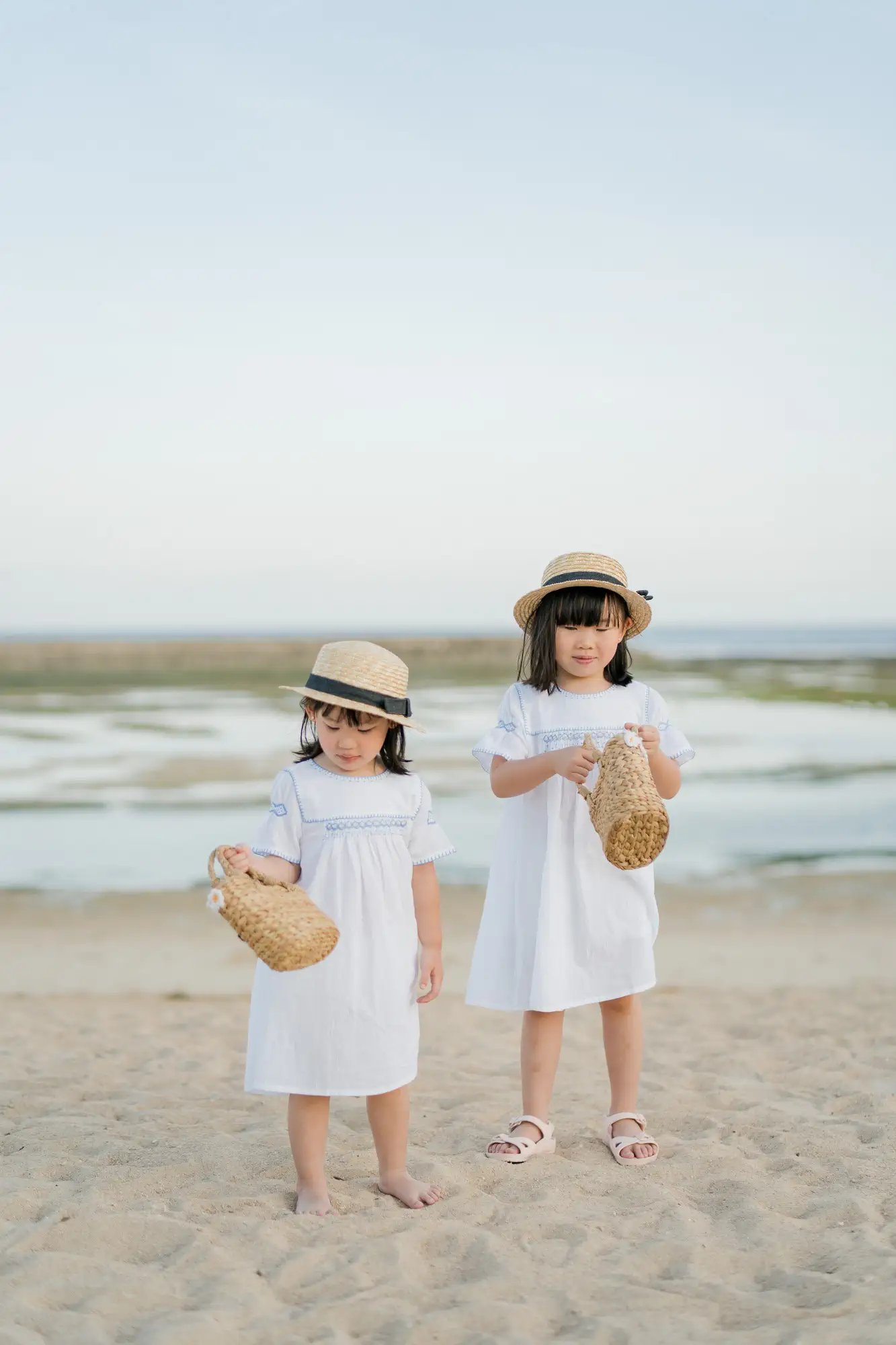 Two sisters standing together on the beach at The Apurva Kempinski Bali.