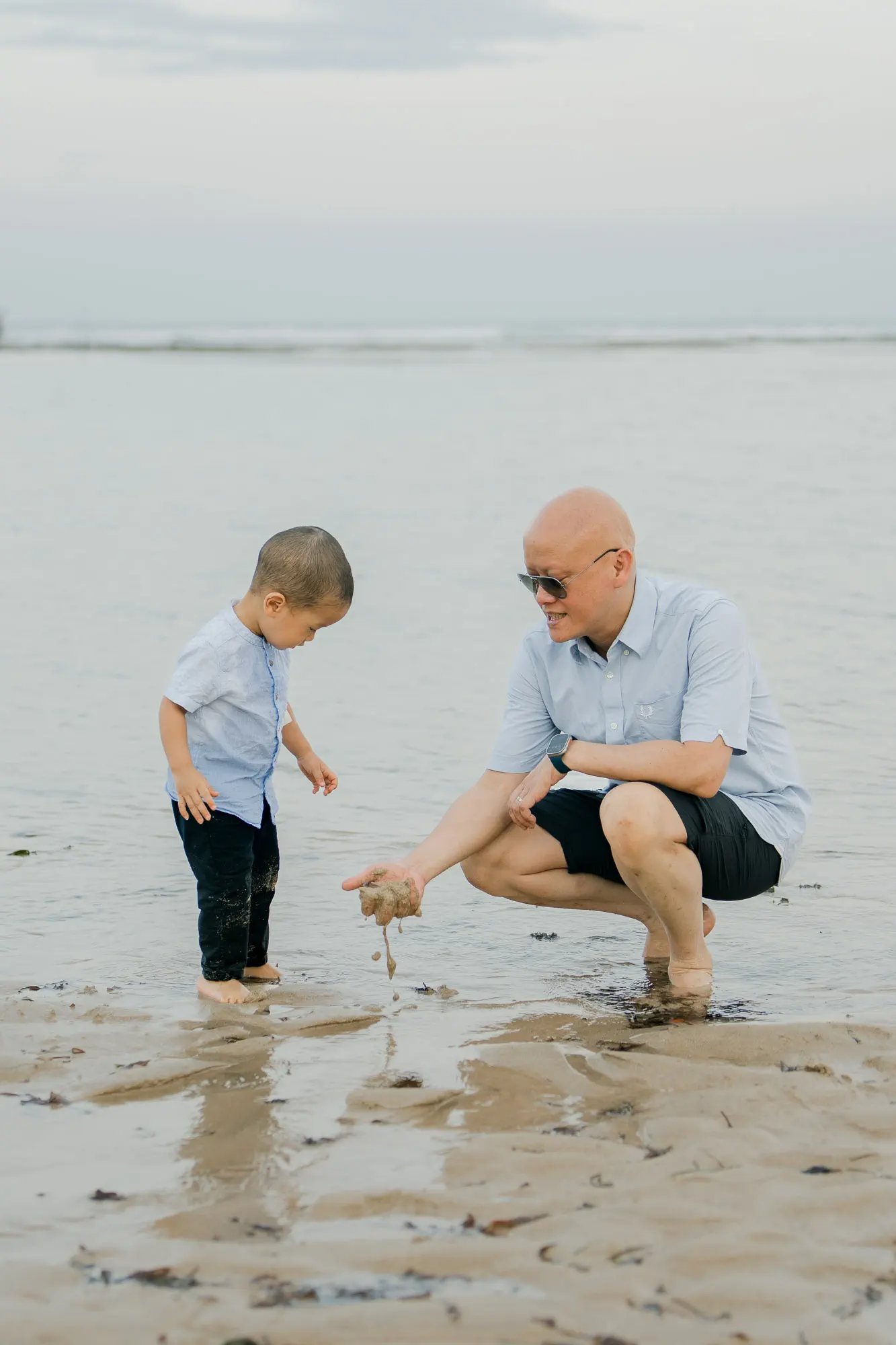 Father and son enjoying quiet moments together on the beach at Nusa Dua Bali
